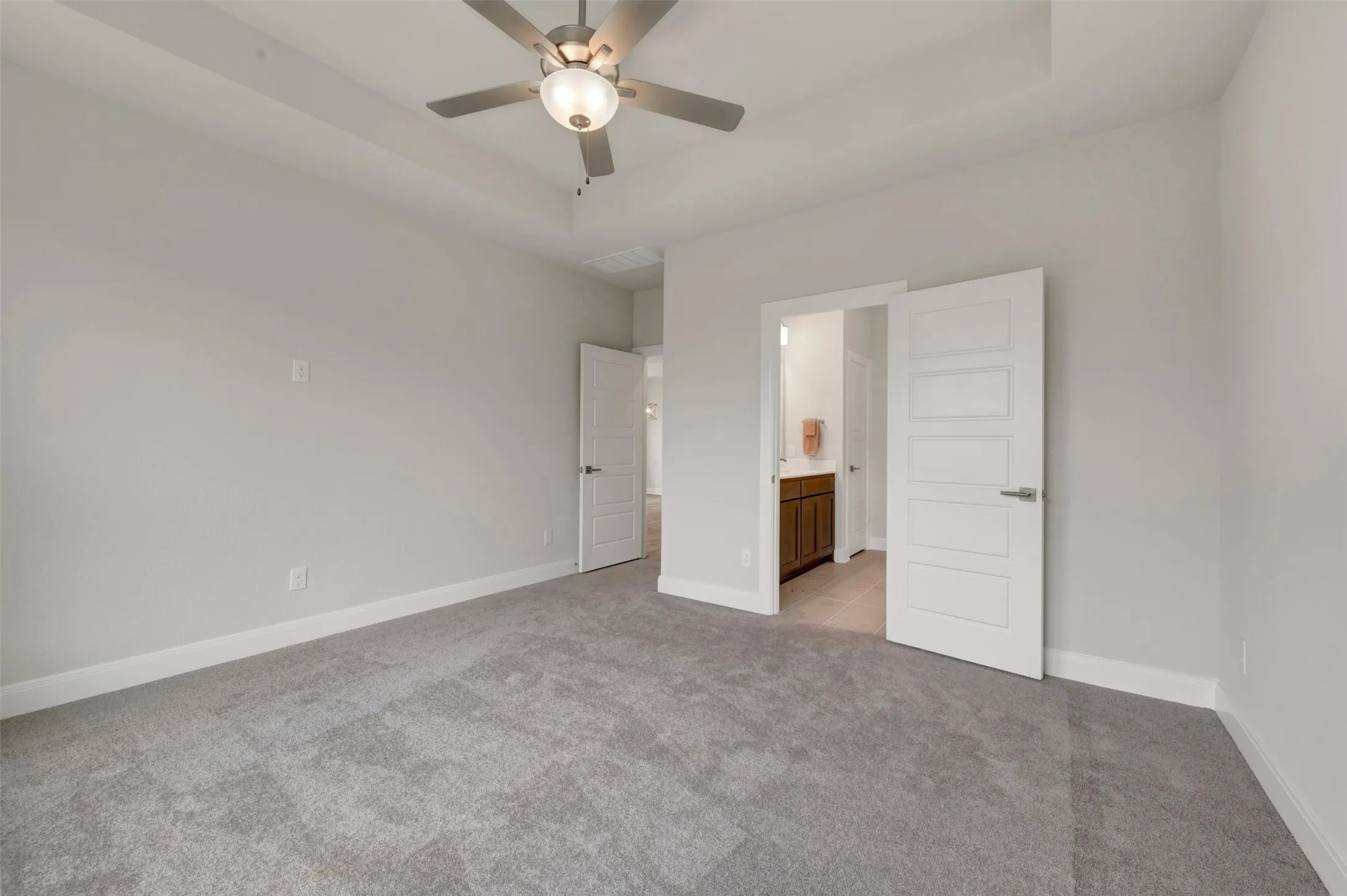 Spacious room with tray ceiling and contemporary ceiling fan