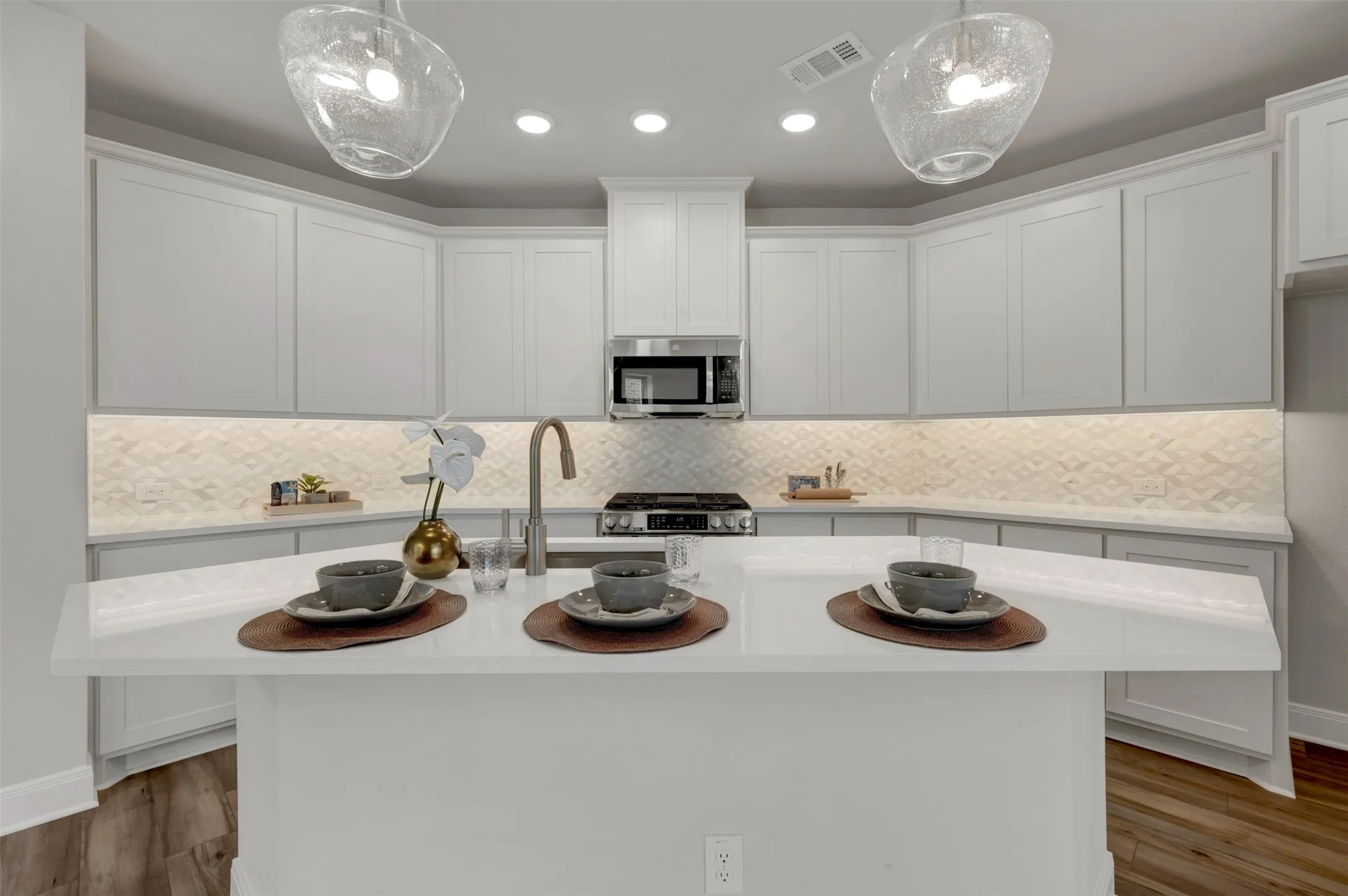 Kitchen featuring a central island with countertop seating, white shaker cabinetry, patterned tile backsplash, recessed lighting, and wood-finish flooring