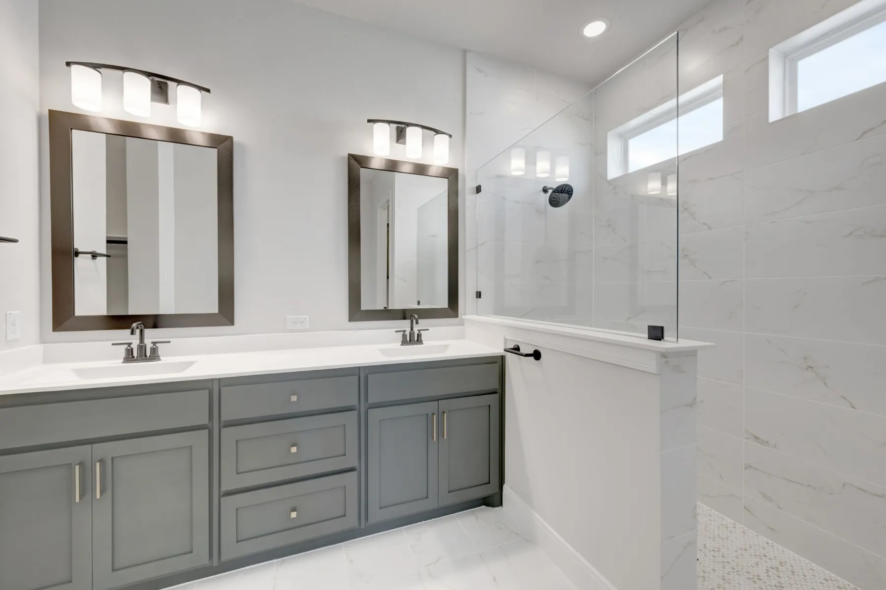 Bathroom featuring double vanity, a marble finish shower, and light marble finish flooring