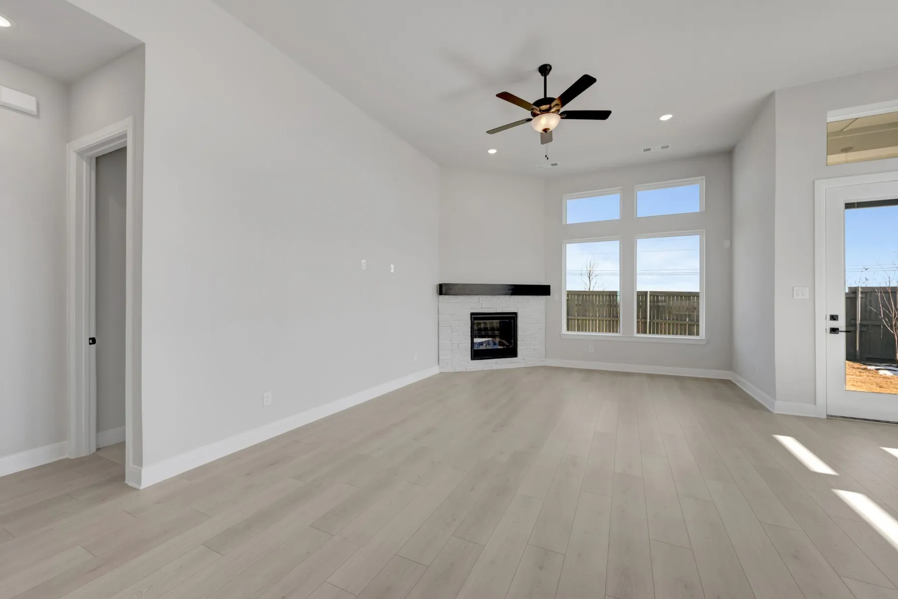 Unfurnished living room with ceiling fan, recessed lighting, a glass covered fireplace, and light wood-style flooring