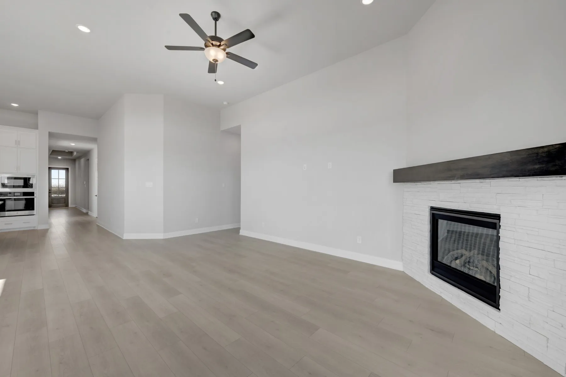 Unfurnished living room with a ceiling fan, recessed lighting, a fireplace, and light wood finished floors