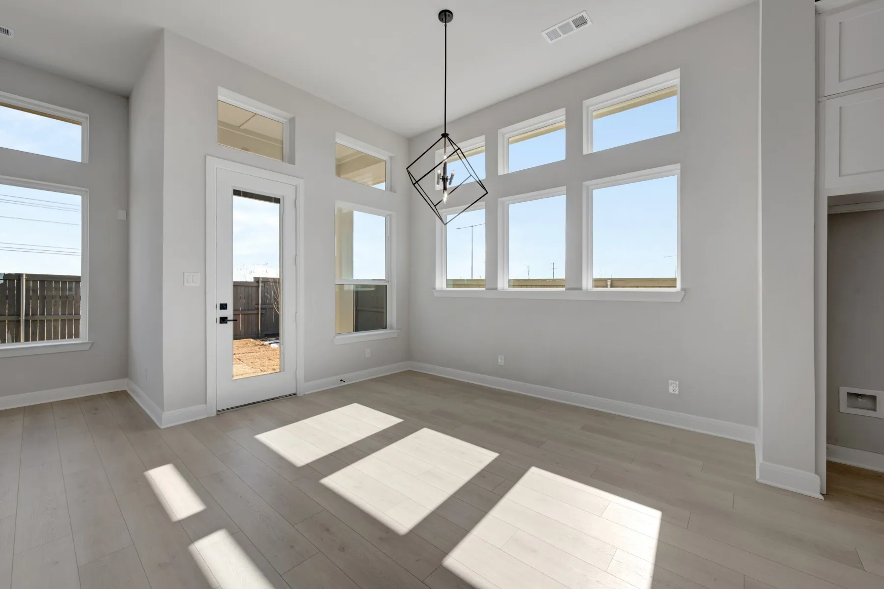 Unfurnished dining area with light wood finished floors, healthy amount of natural light, and suspended lighting