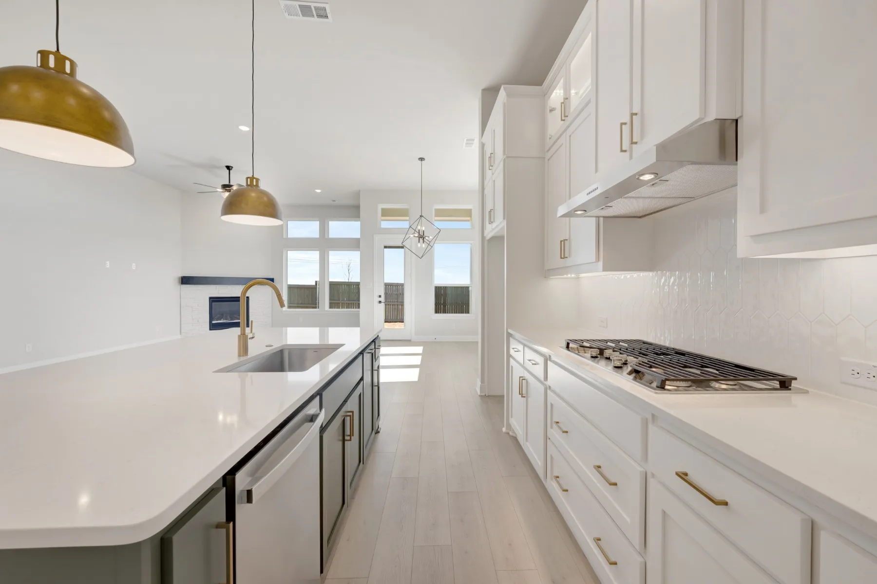 Kitchen with two tone color scheme, a spacious island, stainless steel appliances, a ceiling fan, and hanging light fixtures