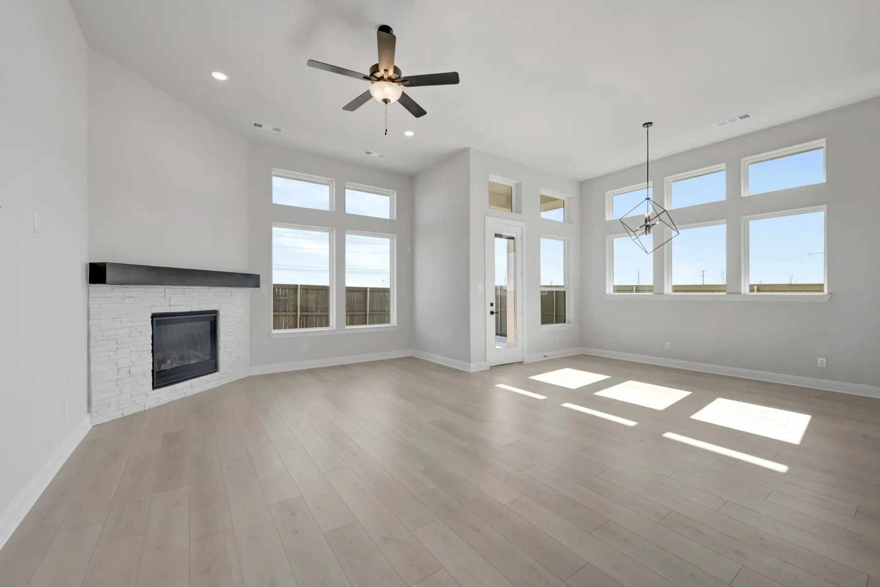 Unfurnished living room with a stone fireplace, ceiling fan, recessed lighting, and light wood-style floors