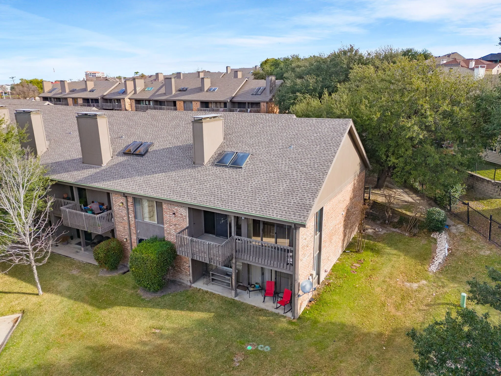 Back of property with a chimney, brick siding, a patio area, a yard, and a residential view