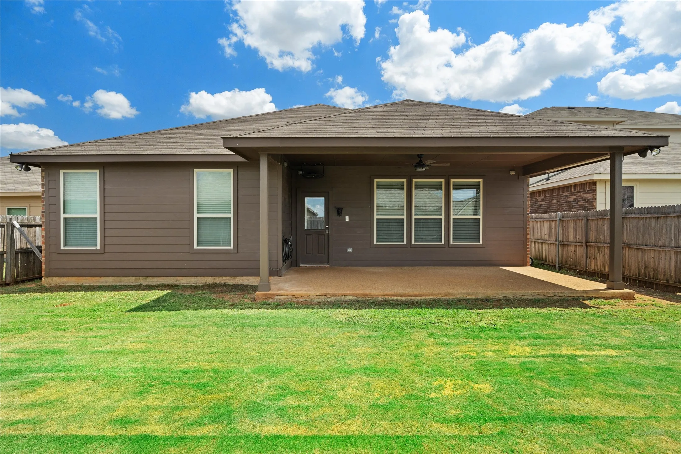 Rear view of property featuring ceiling fan, a patio area, a fenced backyard, and roof with shingles