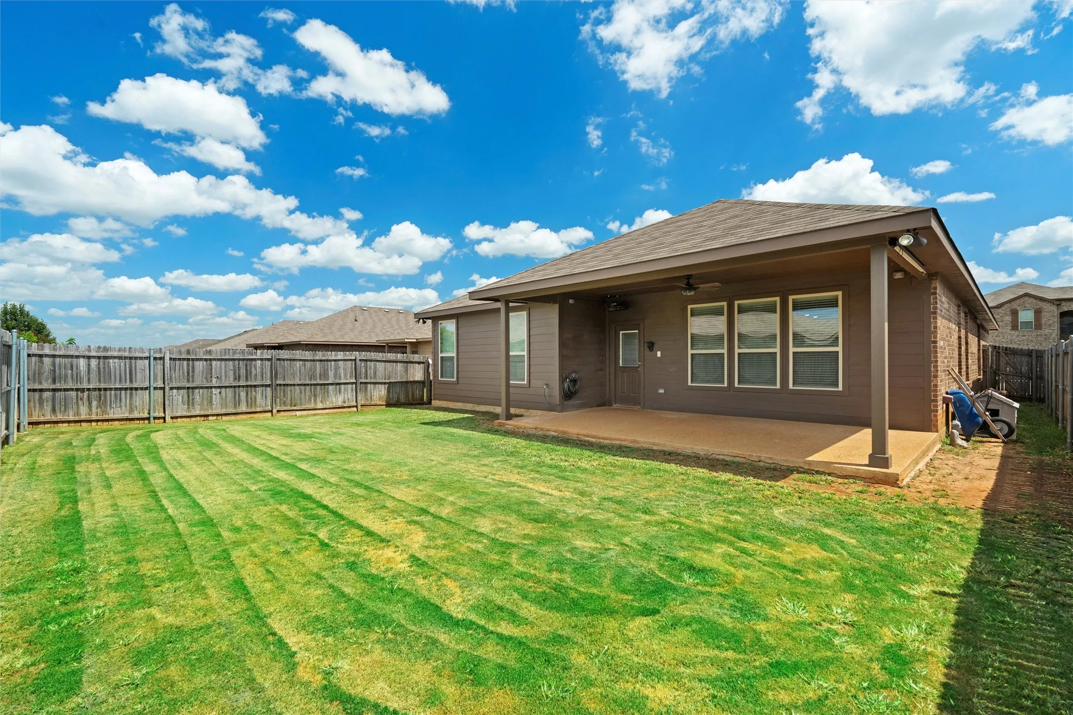 Rear view of house featuring a fenced backyard, ceiling fan, and a patio