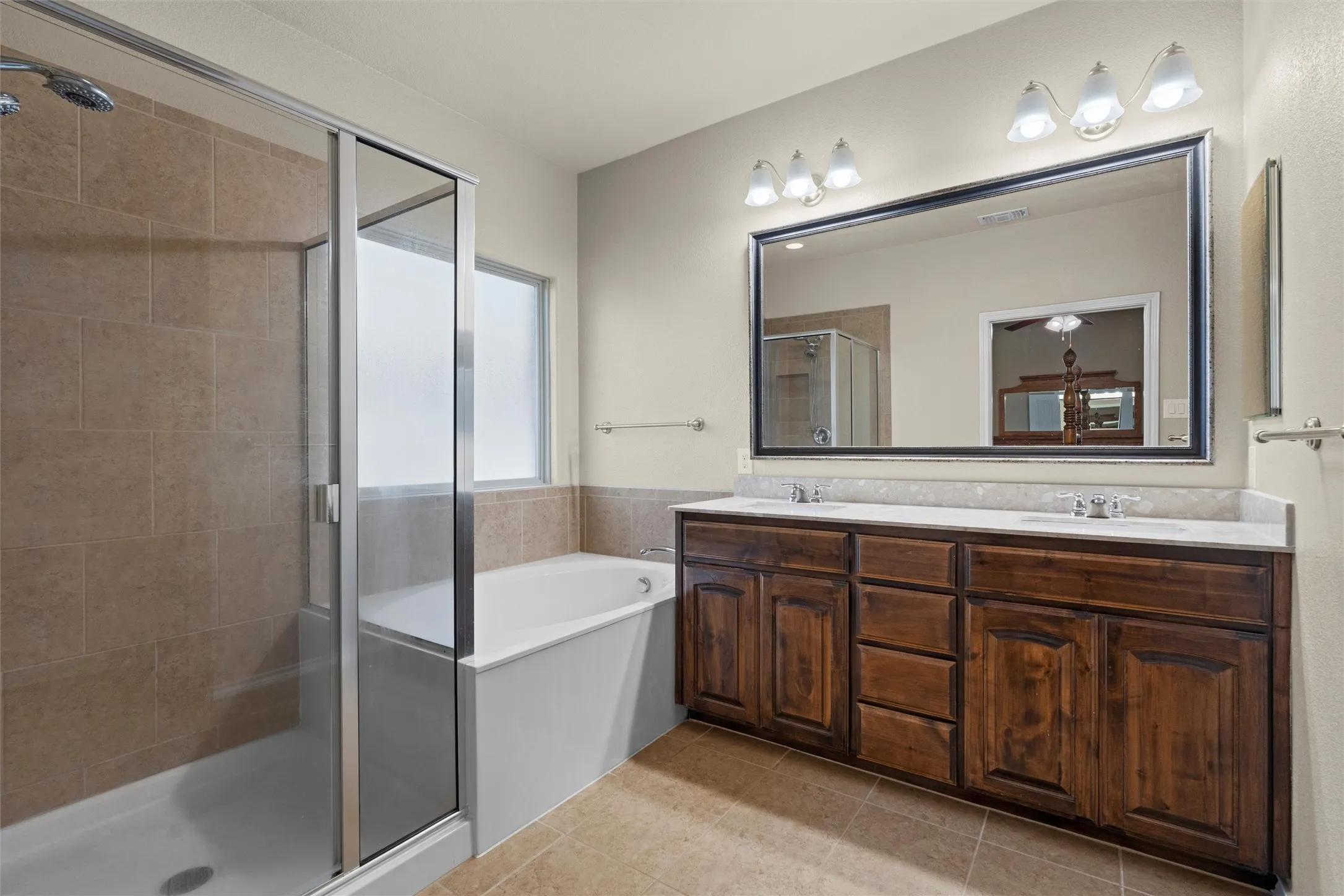 Full bathroom with double vanity, a bath, a stall shower, and light tile patterned floors