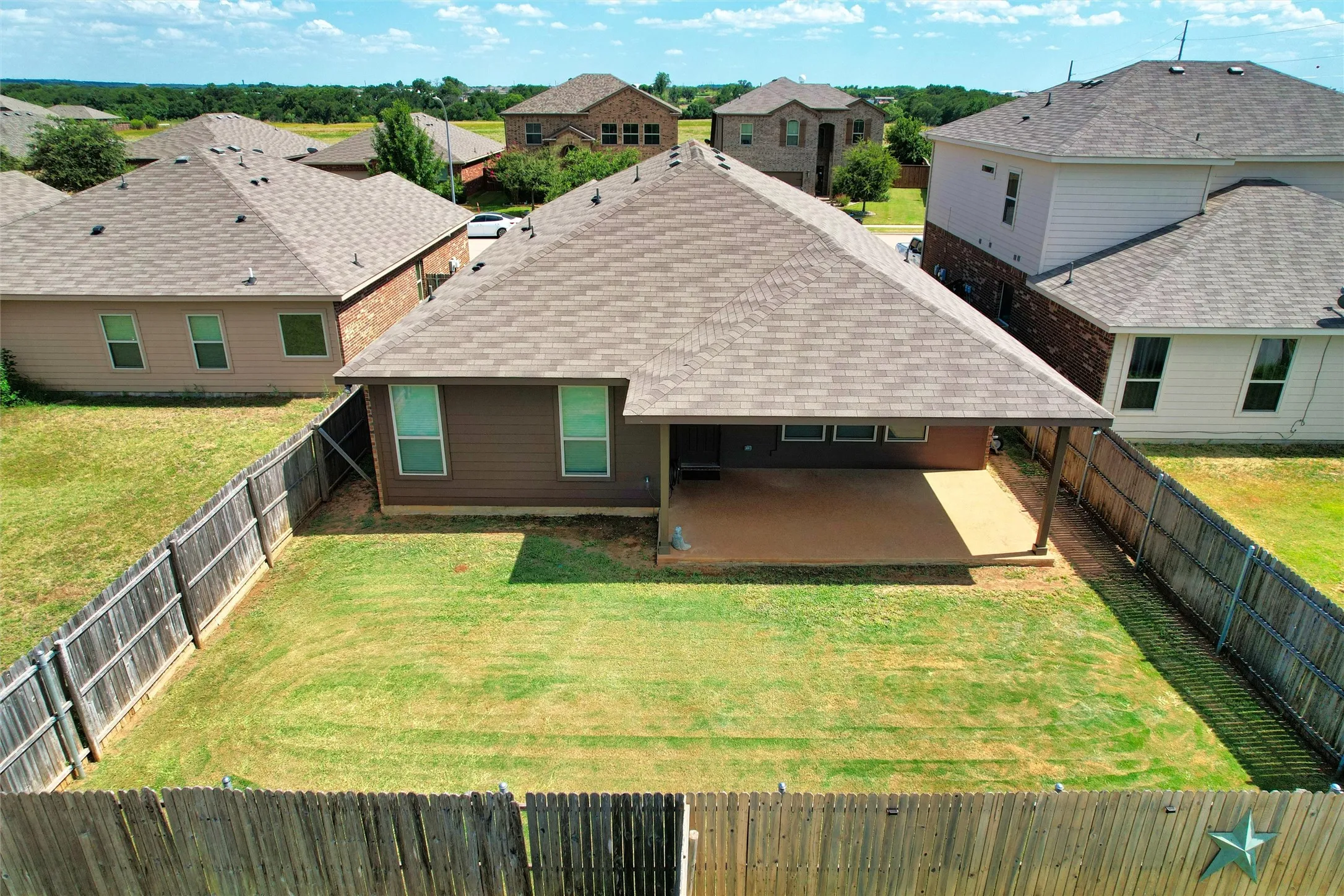 Back of property with a shingled roof, a patio area, a fenced backyard, and a residential view