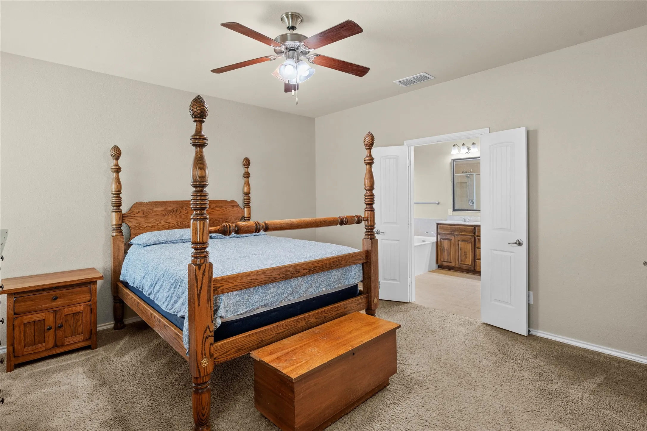 Bedroom with light colored carpet, a ceiling fan, and ensuite bath
