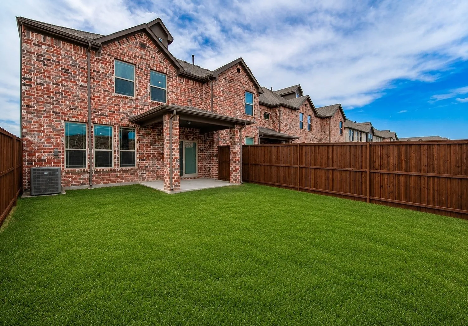 Expansive green lawn featuring a private wooden fence
