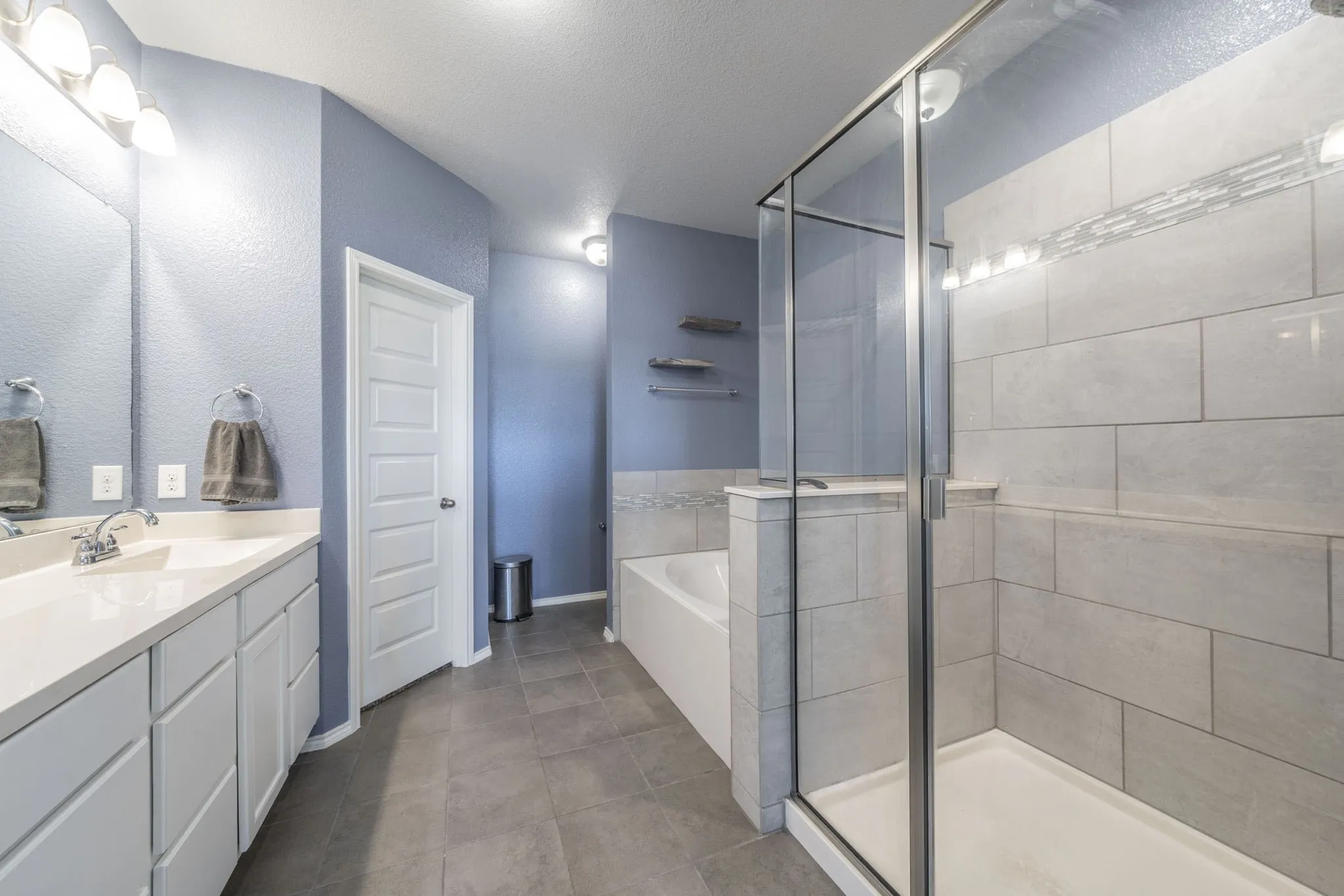 Full bathroom featuring a garden tub, vanity, a shower stall, and a textured ceiling