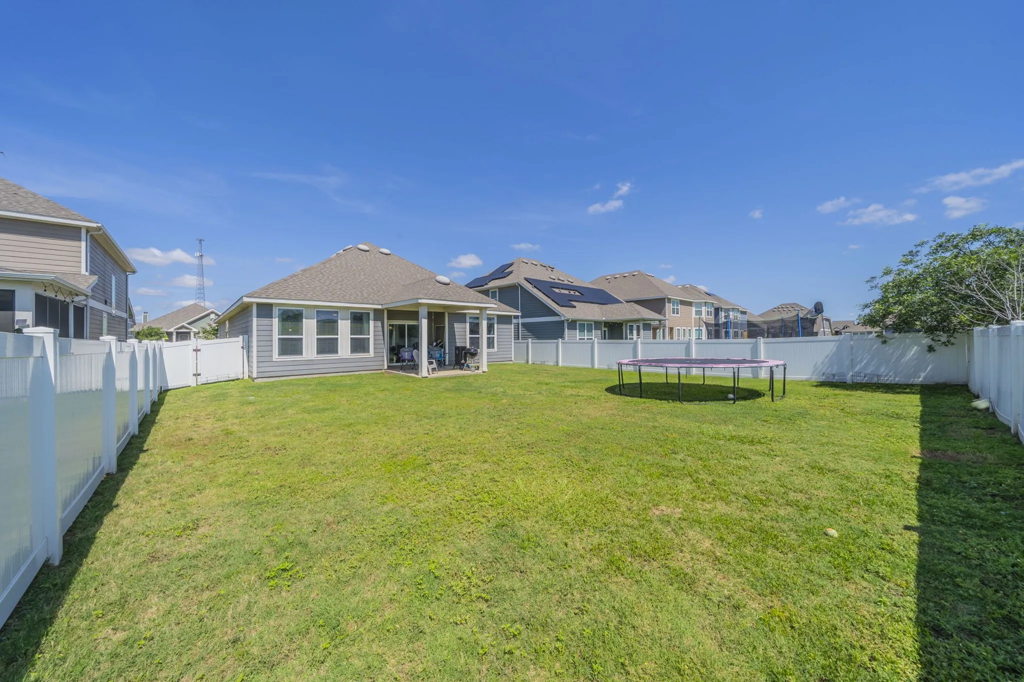 Back of property with a patio area, a fenced backyard, a trampoline, and a residential view