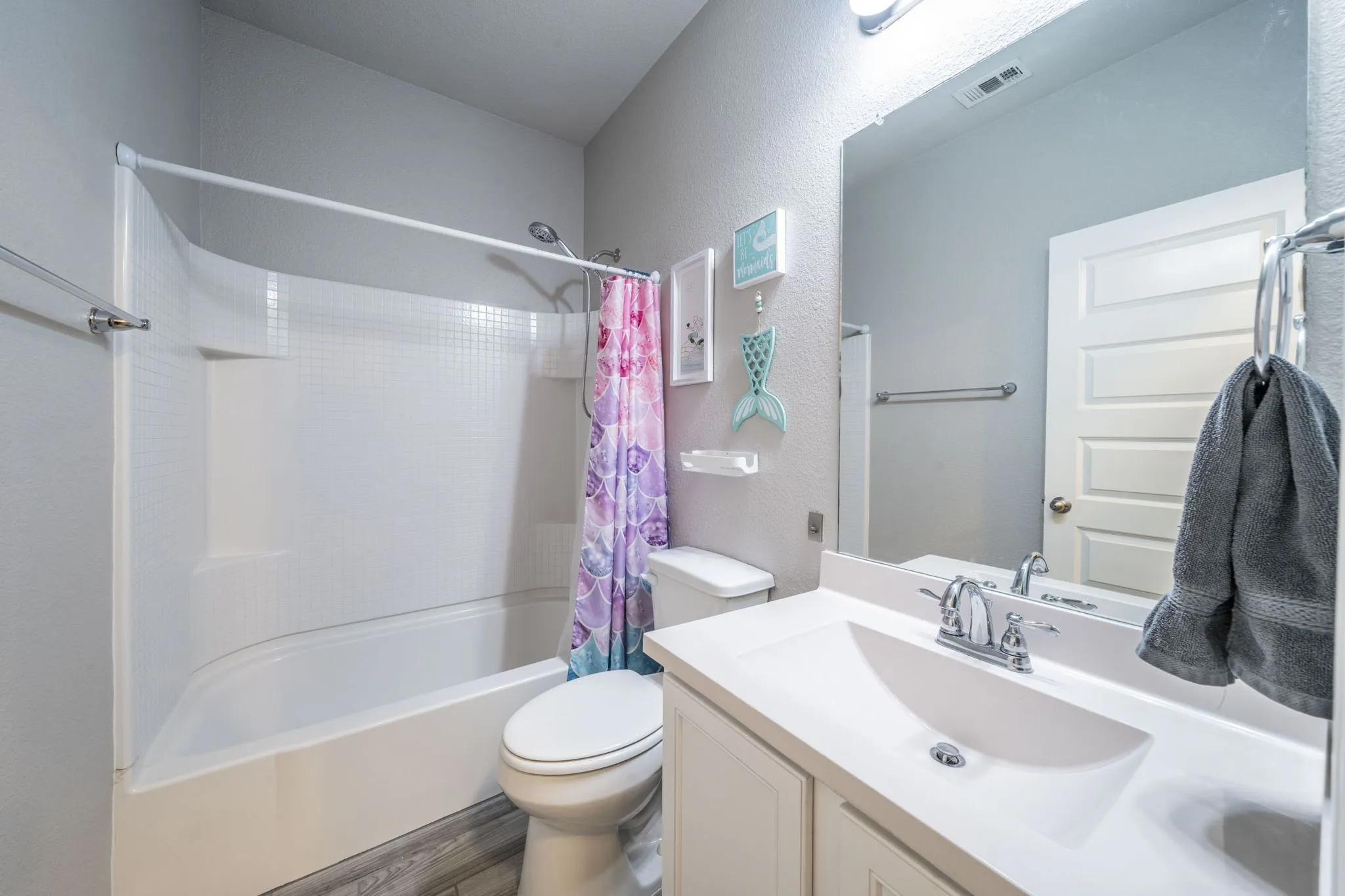 Full bath featuring vanity, shower / tub combo, wood finished floors, and a textured wall