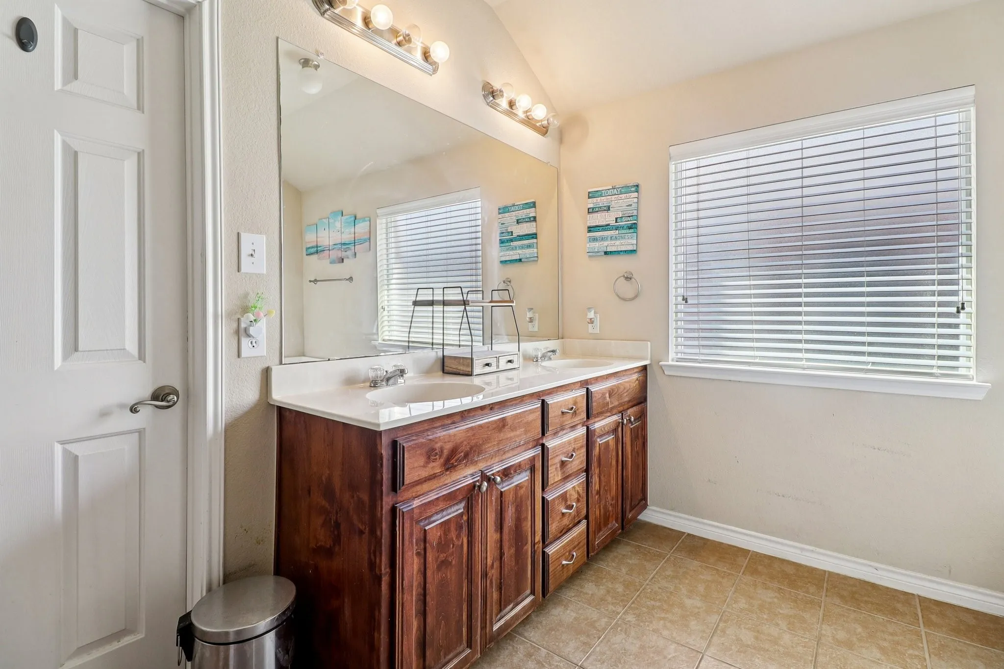 Bathroom with double vanity, light tile patterned flooring, and lofted ceiling