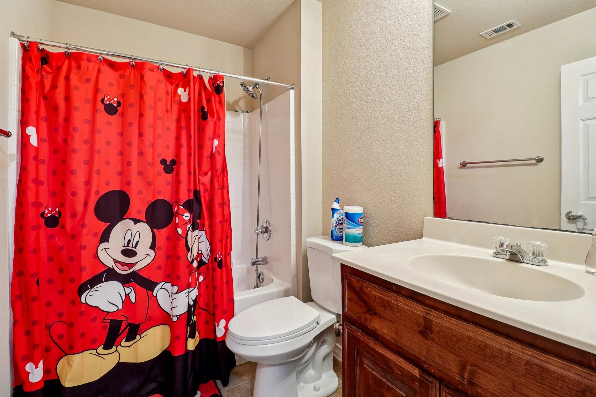 Full bathroom with a textured wall, vanity, and shower / tub combo with curtain