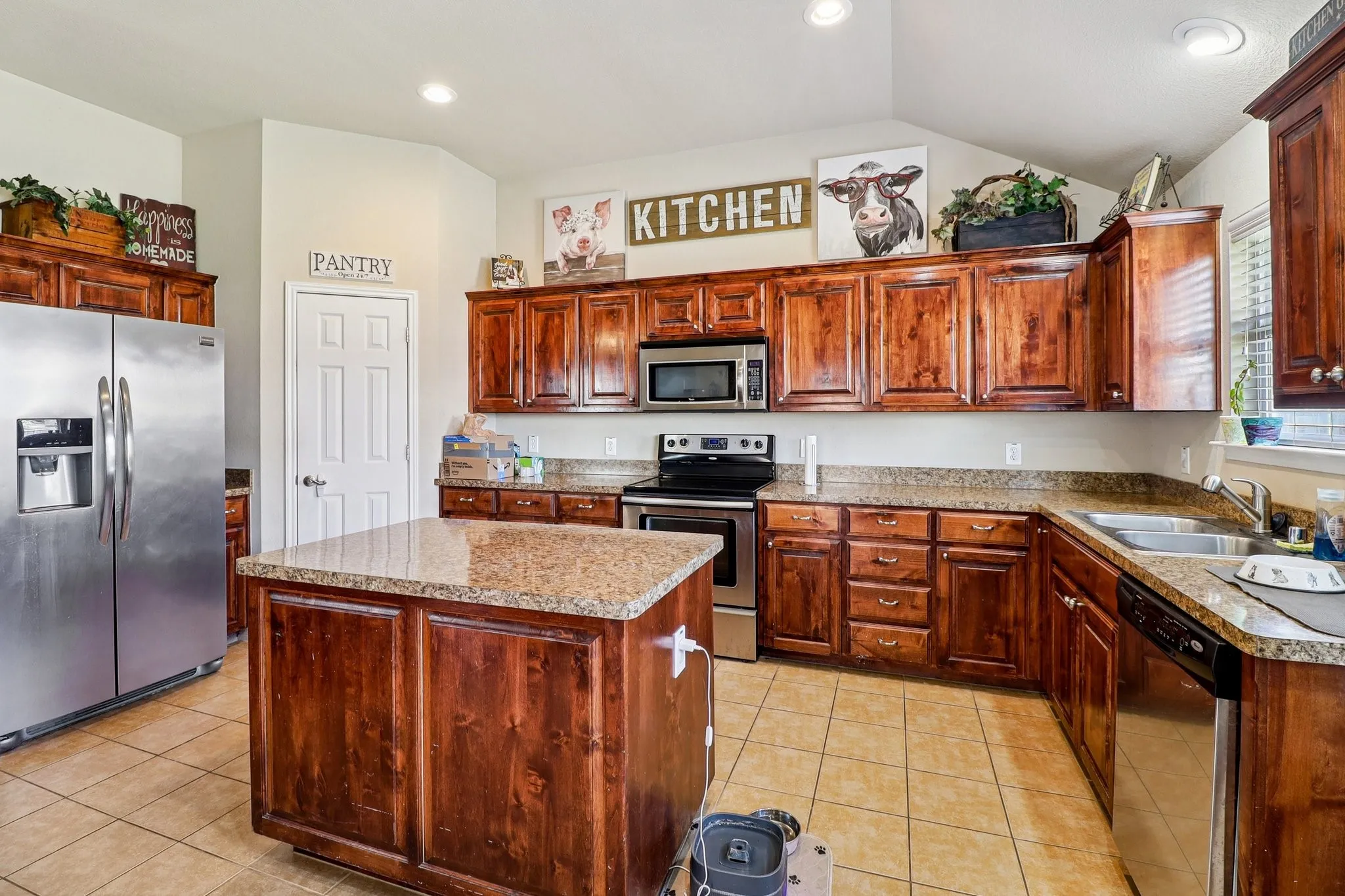 Kitchen with stainless steel appliances, a center island, light tile patterned flooring, lofted ceiling, and recessed lighting