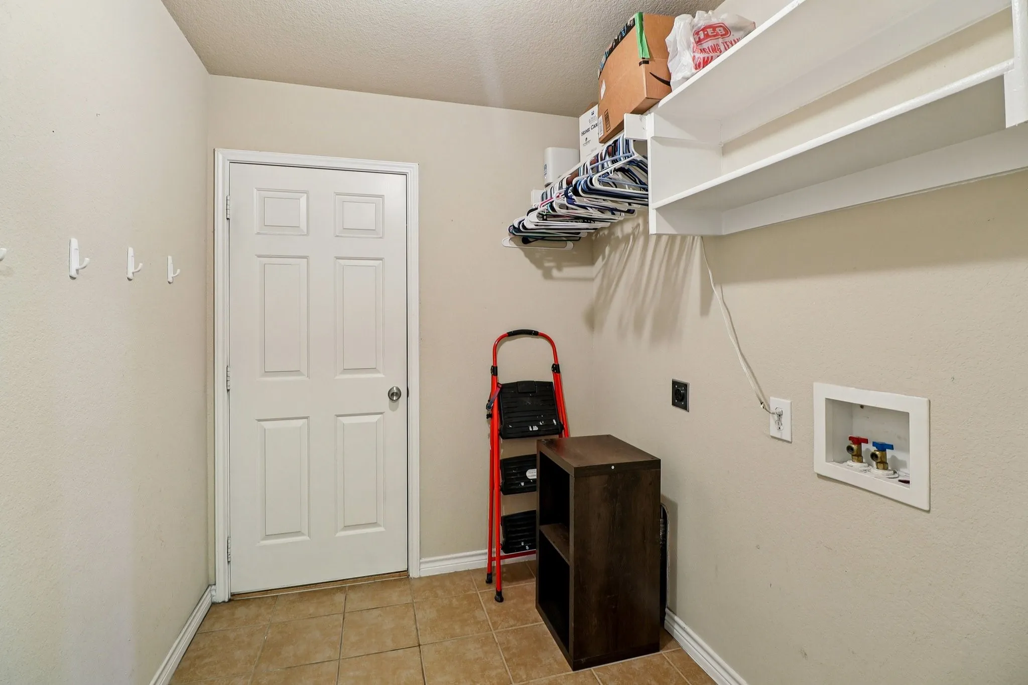 Laundry room featuring a textured ceiling, hookup for a washing machine, and light tile patterned flooring