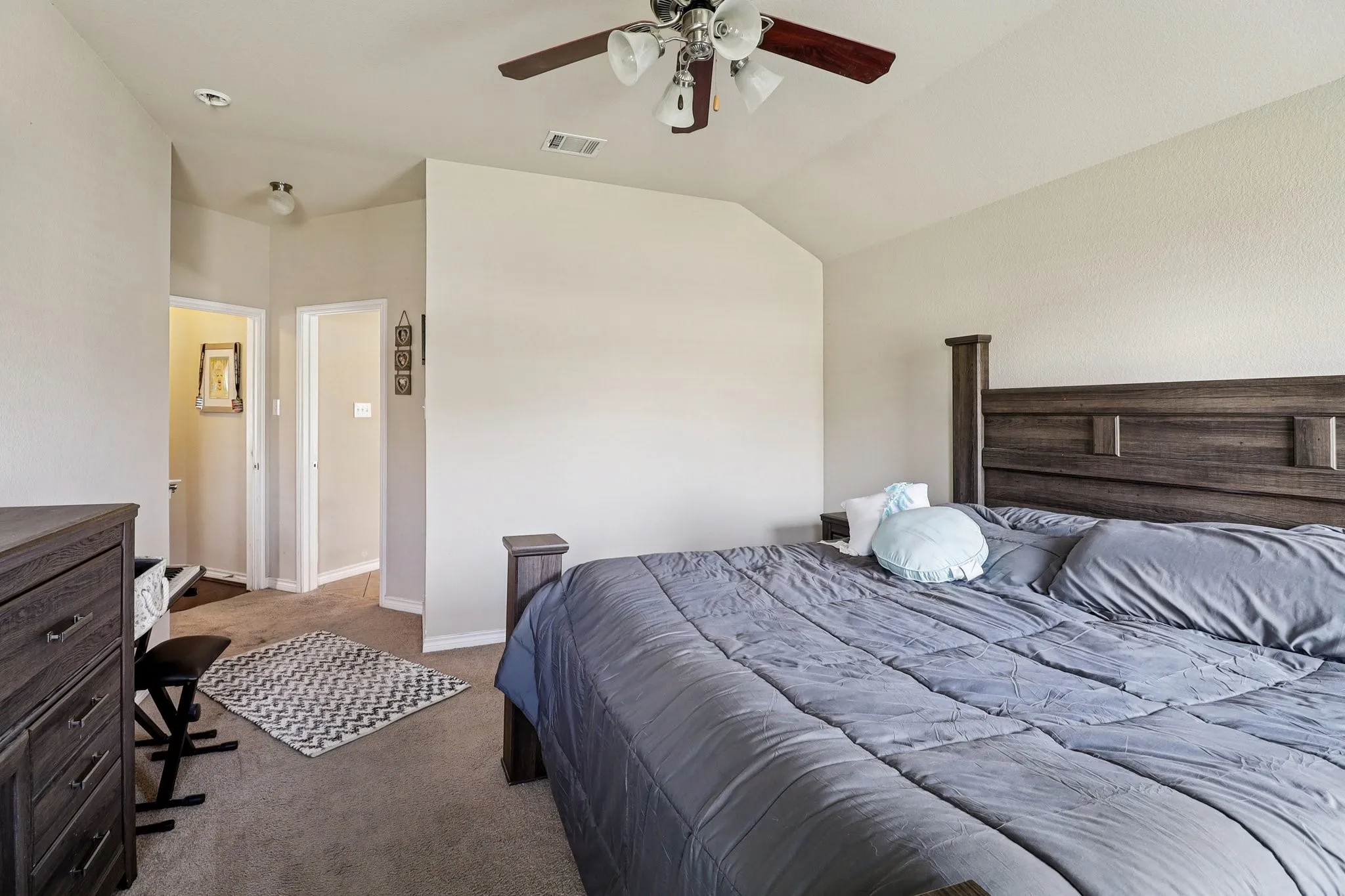 Bedroom with dark colored carpet, lofted ceiling, and ceiling fan