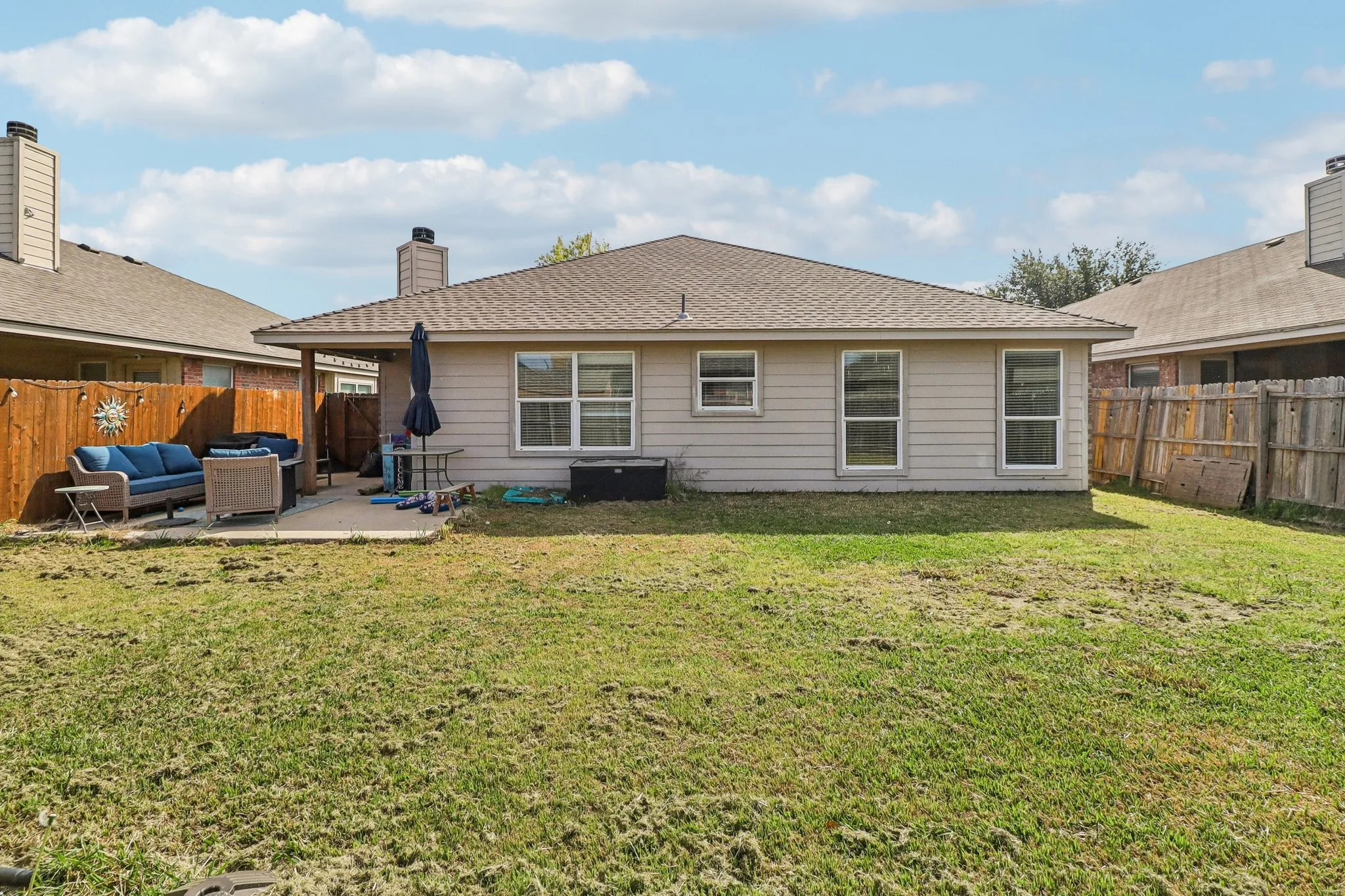 Back of property featuring an outdoor lounge area, a patio area, a fenced backyard, a shingled roof, and a chimney