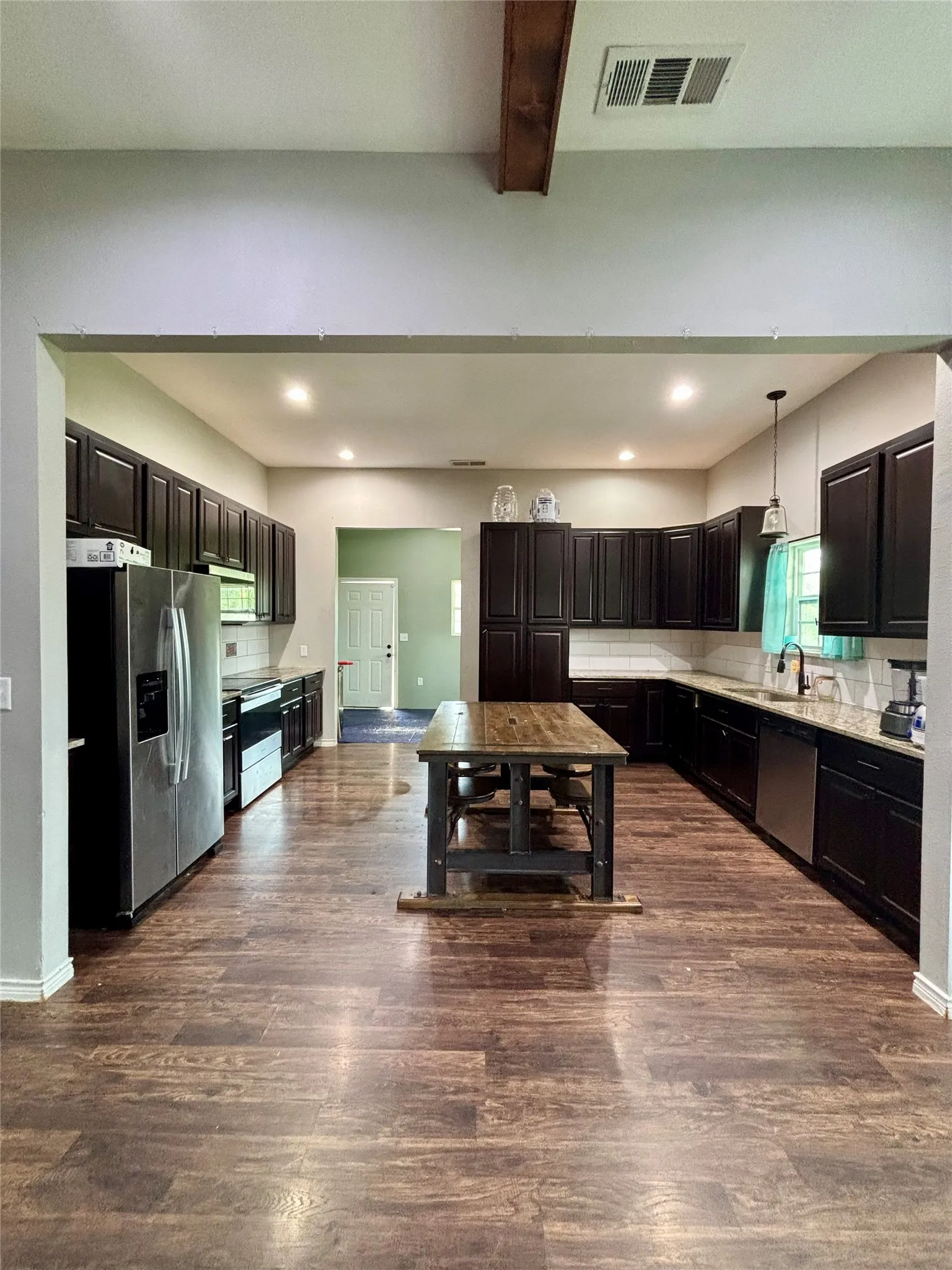 Spacious kitchen featuring extensive dark wood cabinetry, stainless steel appliances, and wood-finish flooring