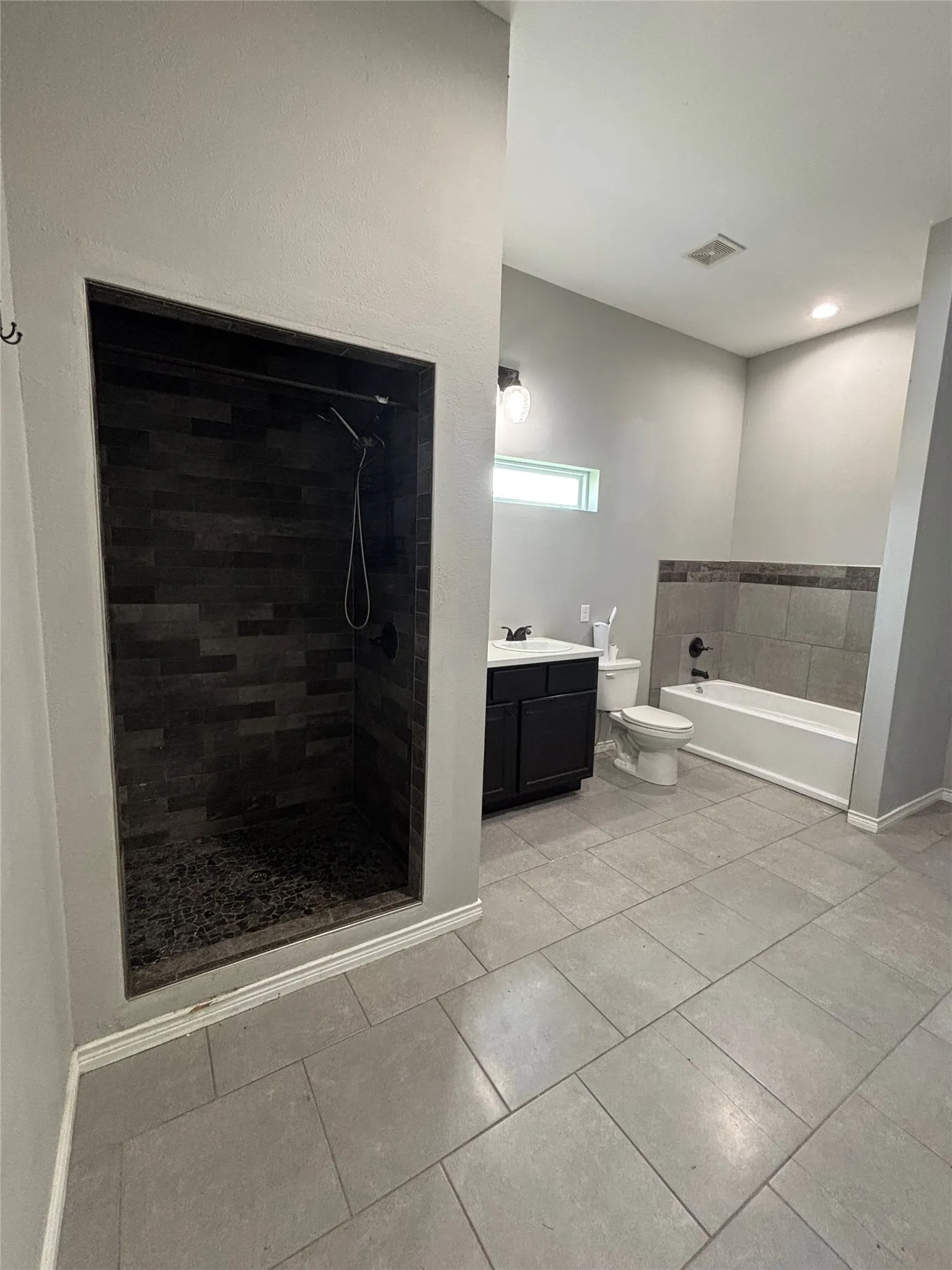Walk-in shower featuring dark-toned stacked tile and a black shower fixture