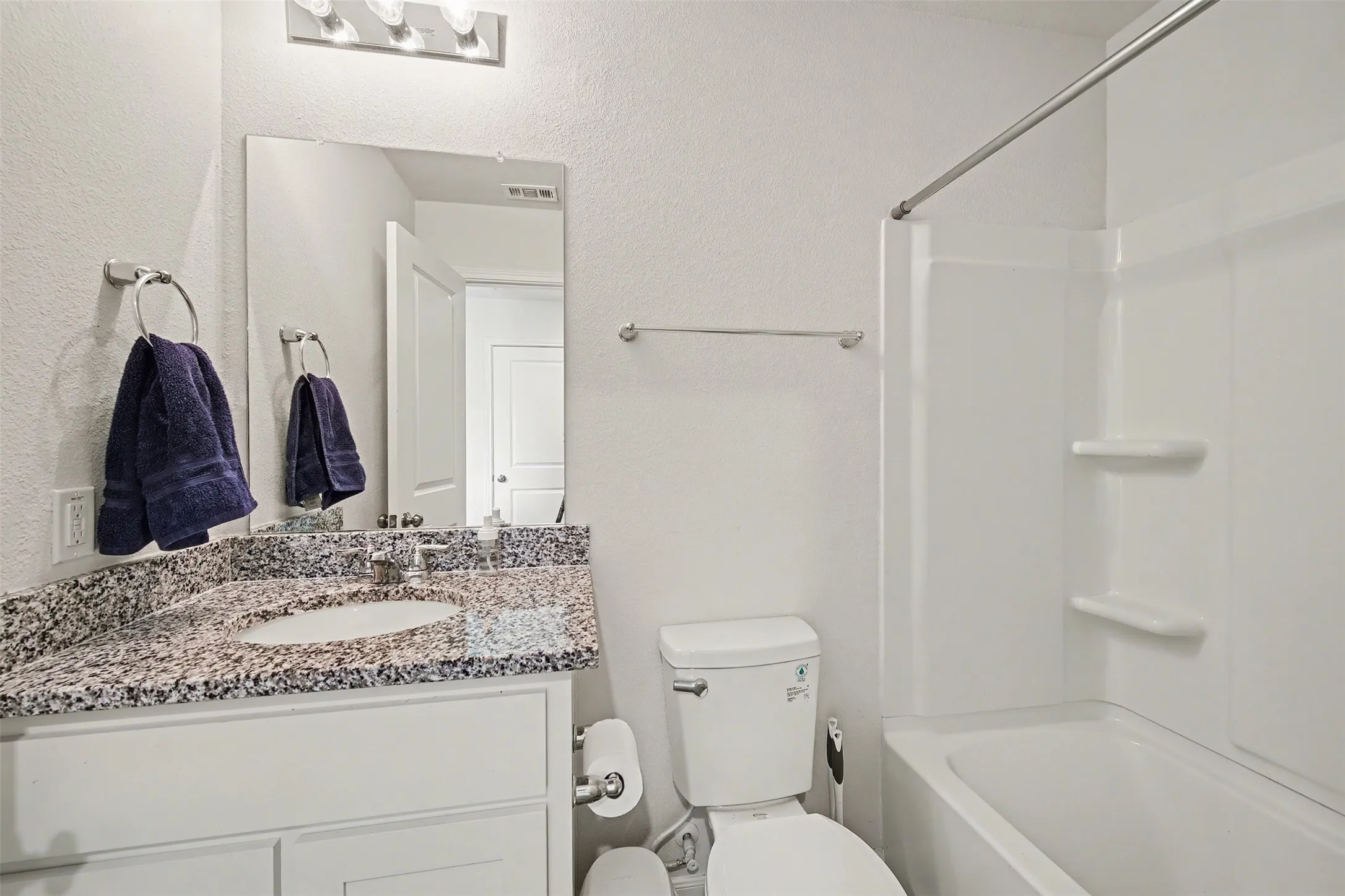 Full bath with vanity, shower / bathtub combination, and a textured wall