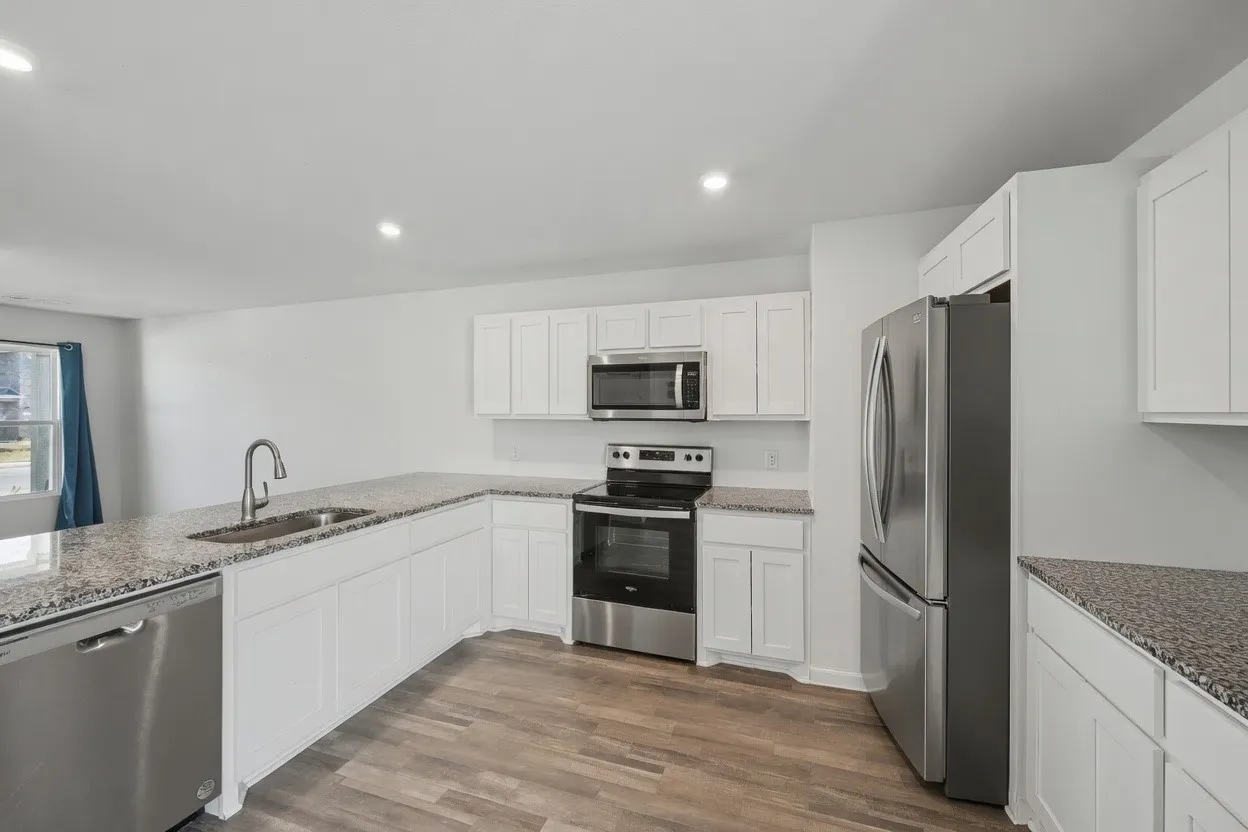 Kitchen featuring white cabinetry, speckled countertops, stainless steel appliances, and wood-finish flooring
