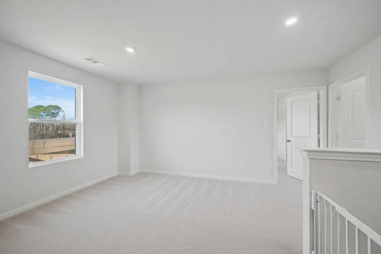 Plush carpeting, recessed lighting, and a large window providing natural illumination