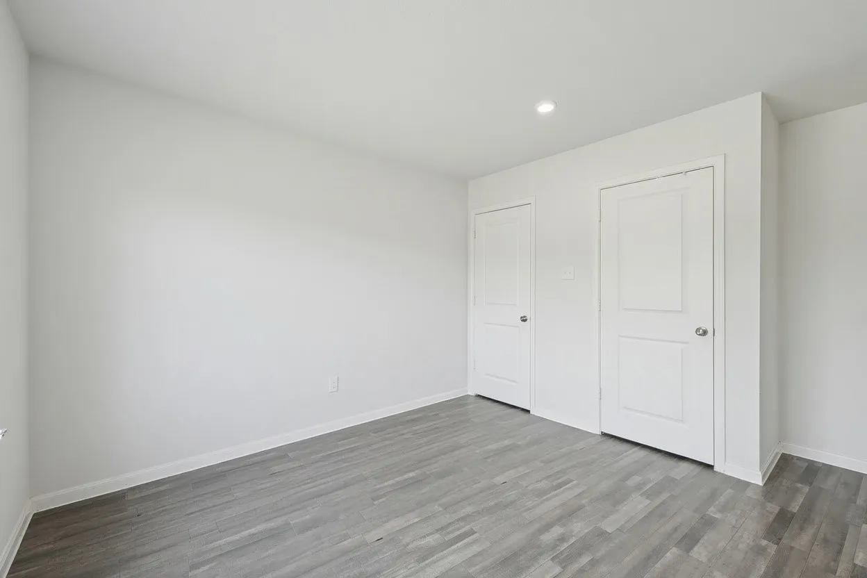 Wood-finish flooring, white trim, recessed lighting, and two panel doors