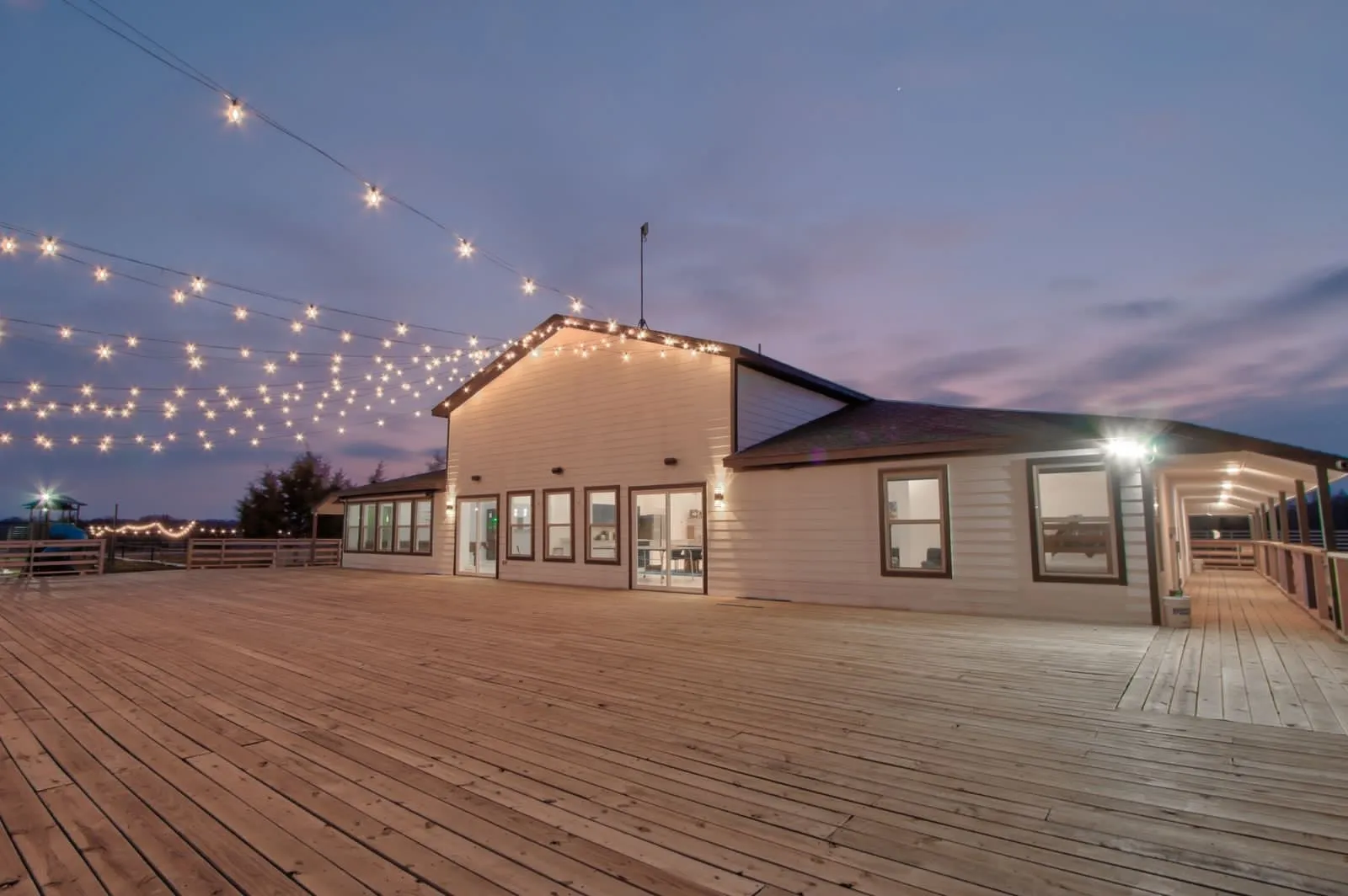 Back of structure featuring a large deck and decorative string lighting.