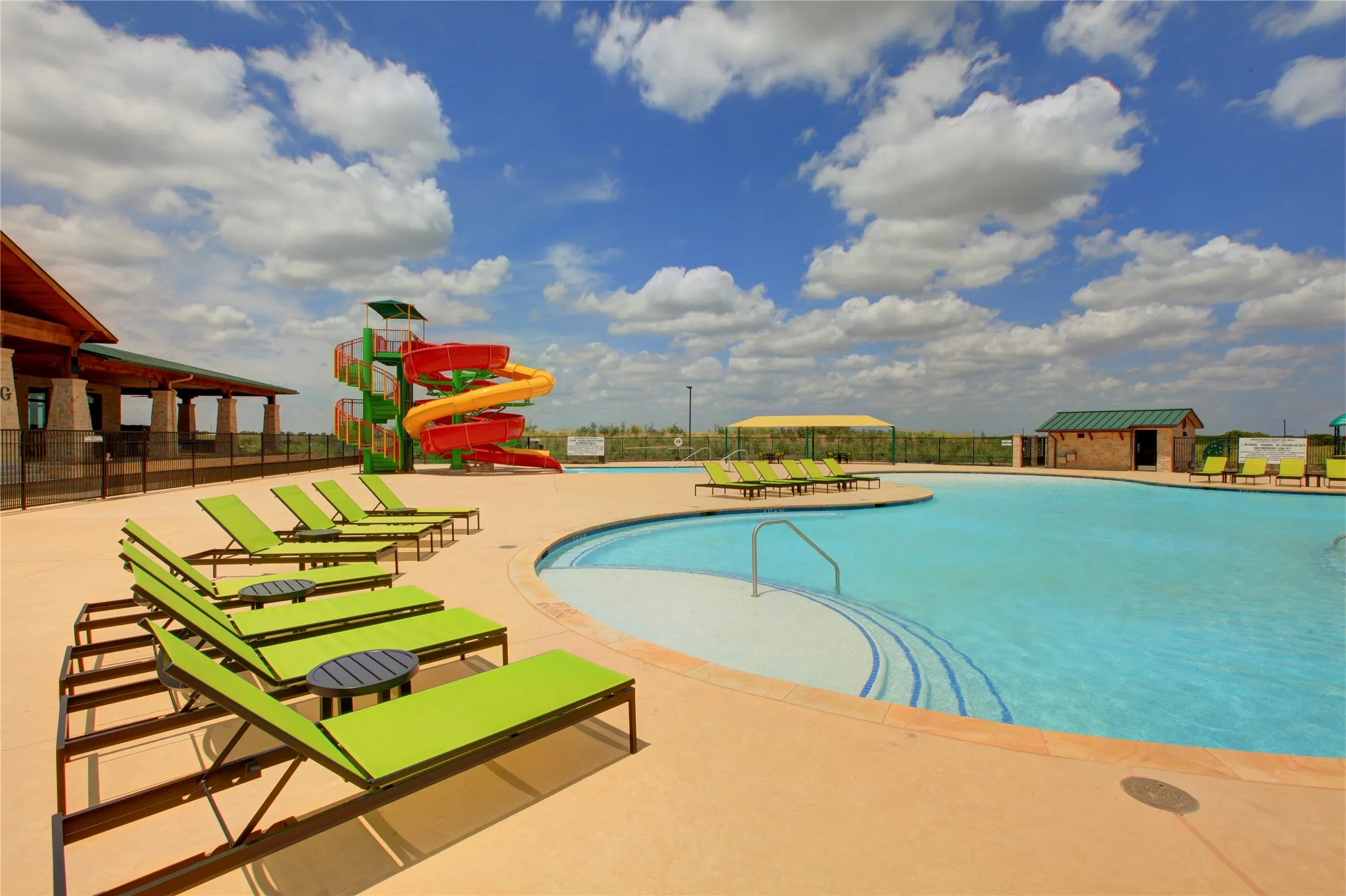 Expansive community pool featuring a curved design, integrated steps, and a surrounding tan deck