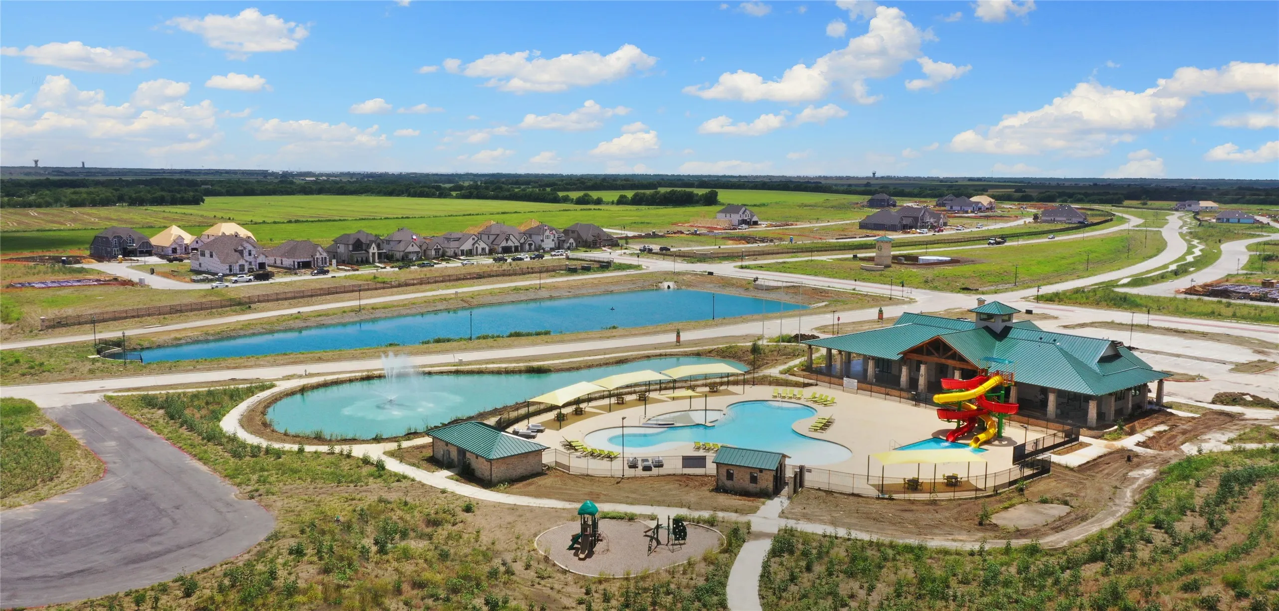 Community amenities featuring a central clubhouse, two swimming pools, a water play structure, and multiple ponds with fountains
