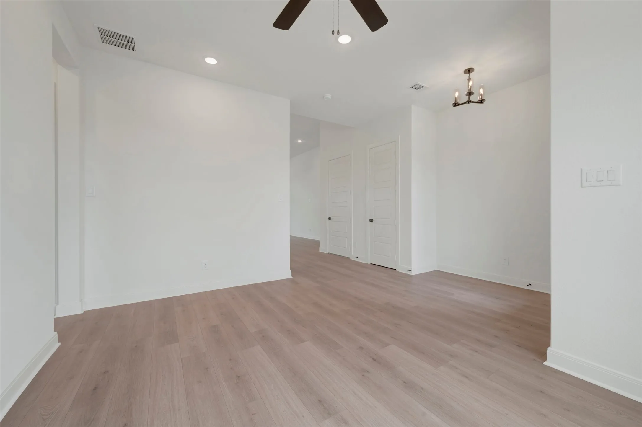 Spacious interior featuring wood-finish flooring, white walls, recessed lighting, and a ceiling fan