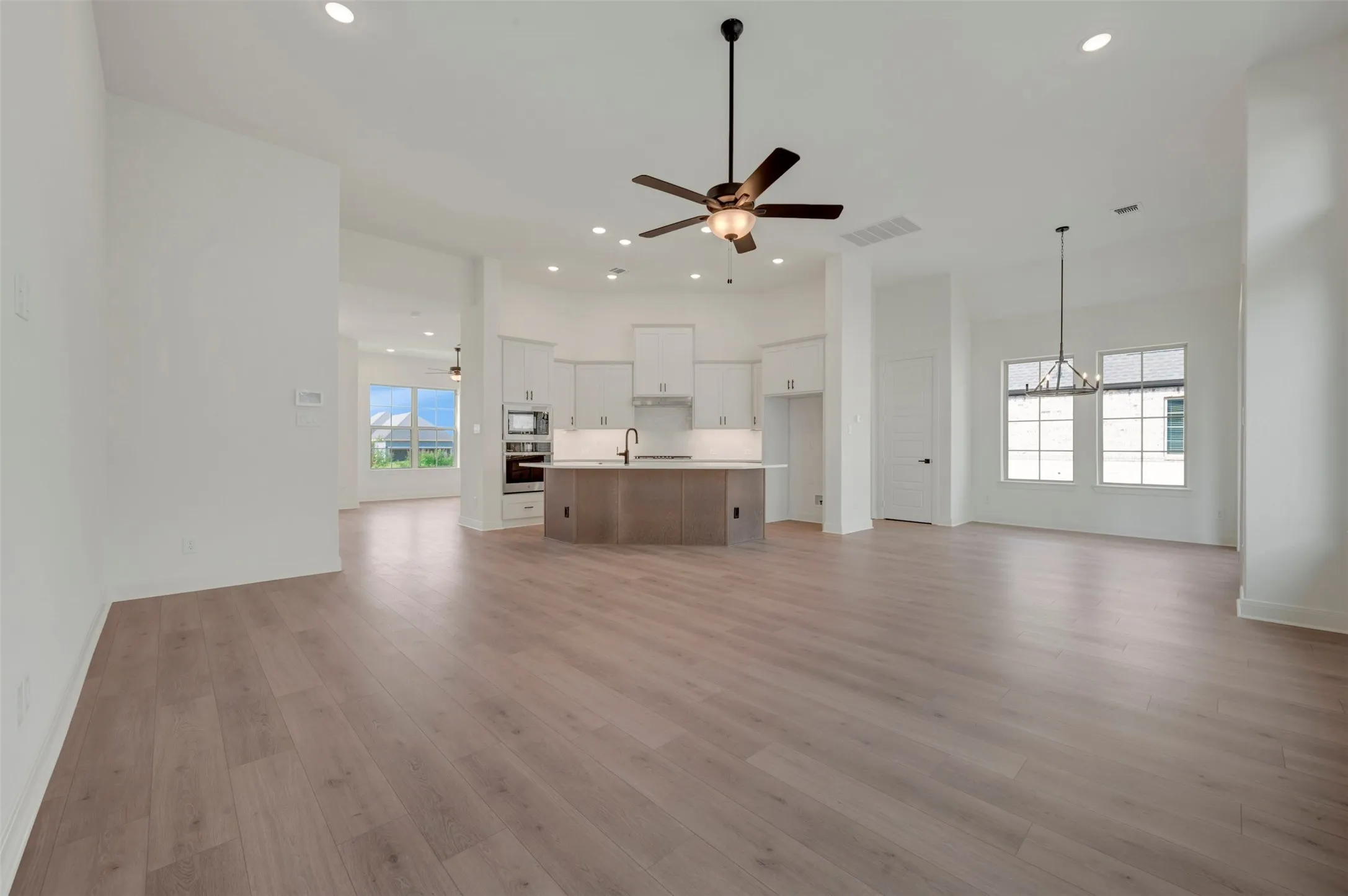 Spacious living area featuring wood-finish flooring and a contemporary ceiling fan