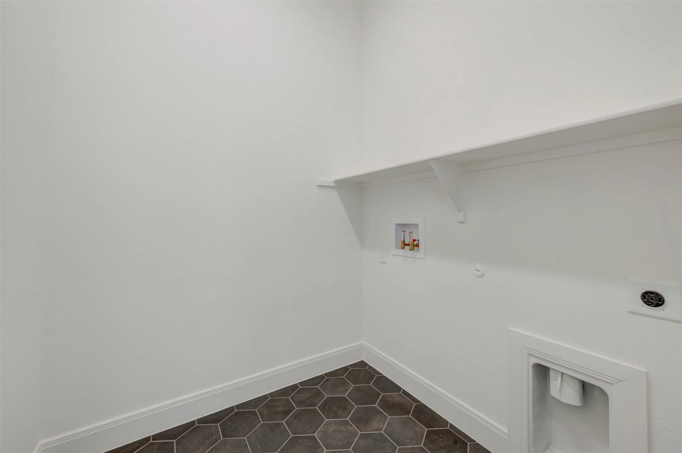 Laundry area featuring hexagonal floor tiles and a wall-mounted shelving unit