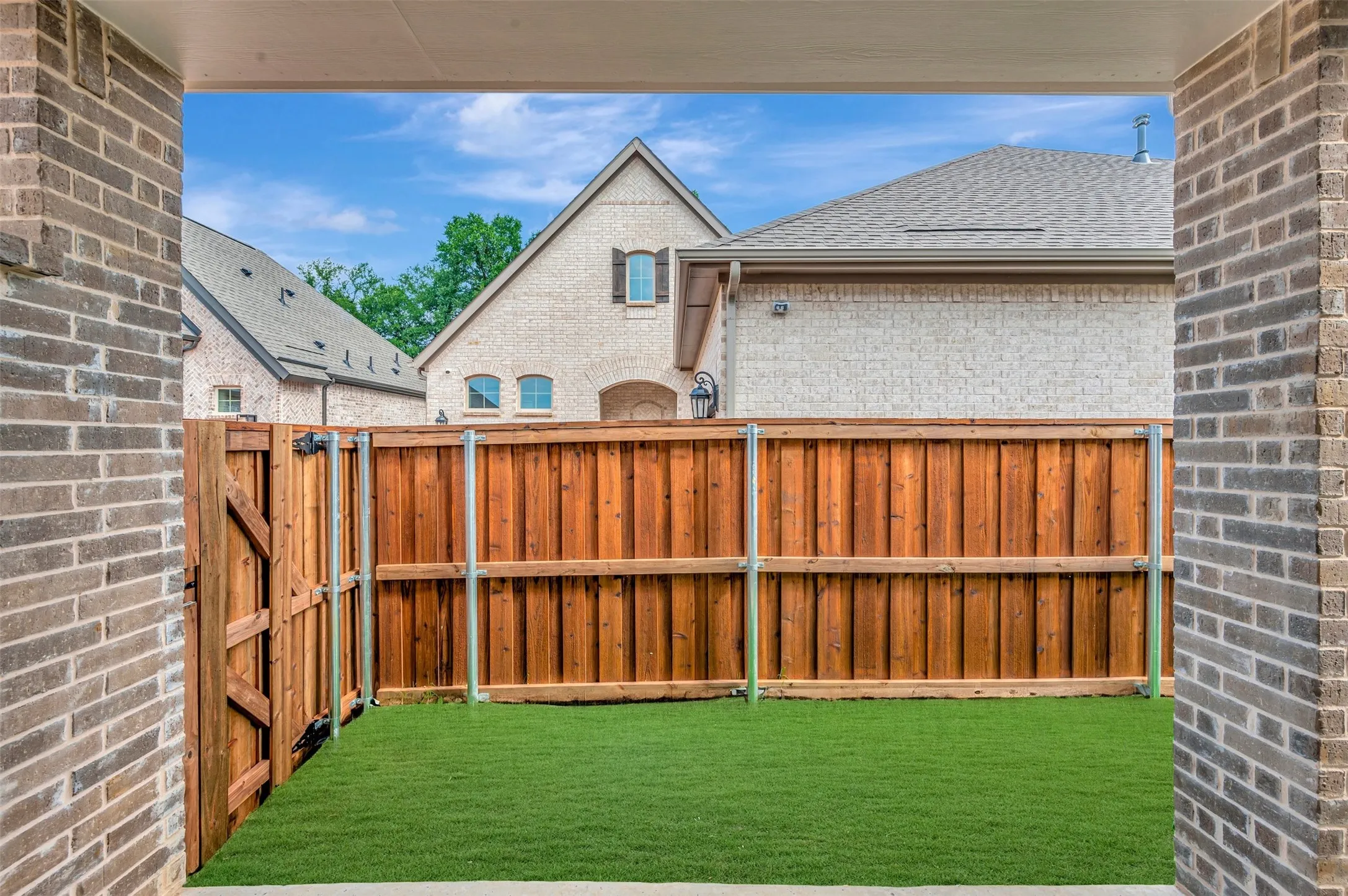 Private backyard featuring a new wood fence, a full-height access gate, and artificial turf