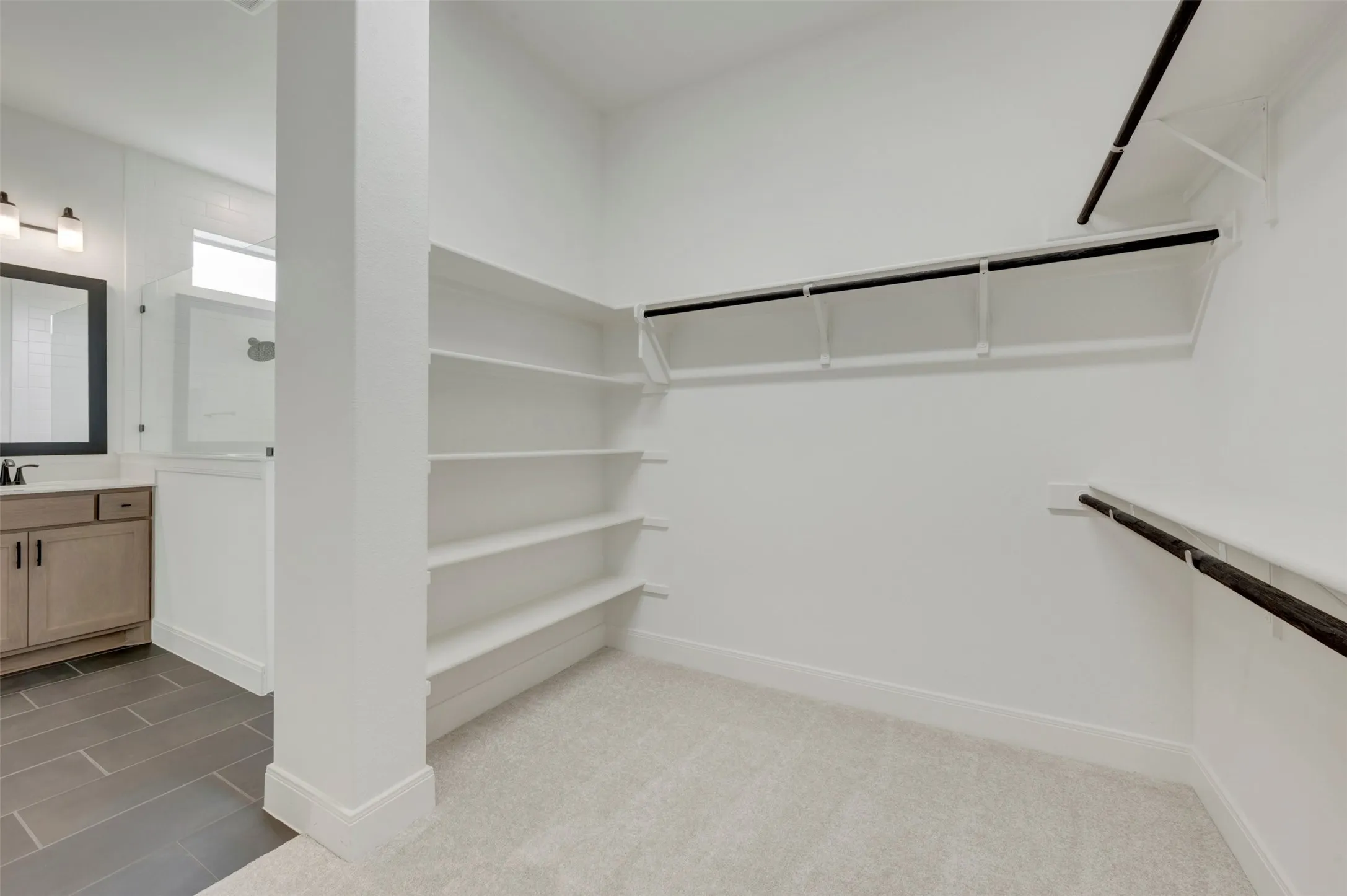 Walk-in closet featuring built-in shelving, multiple hanging rods, and light-toned carpeting