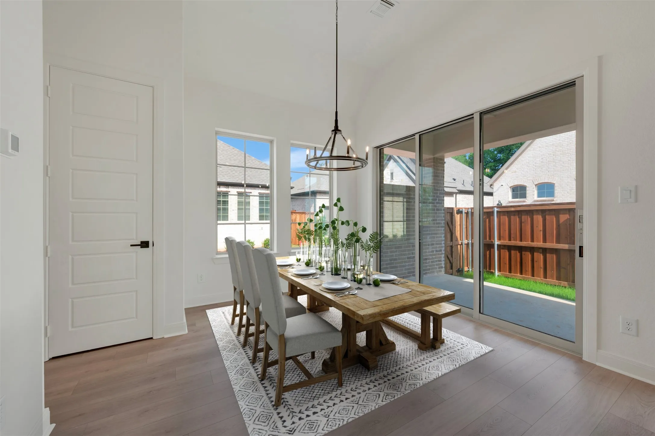 Spacious interior featuring wood-finish flooring, two large windows, and a sliding glass door providing access to the outdoor patio