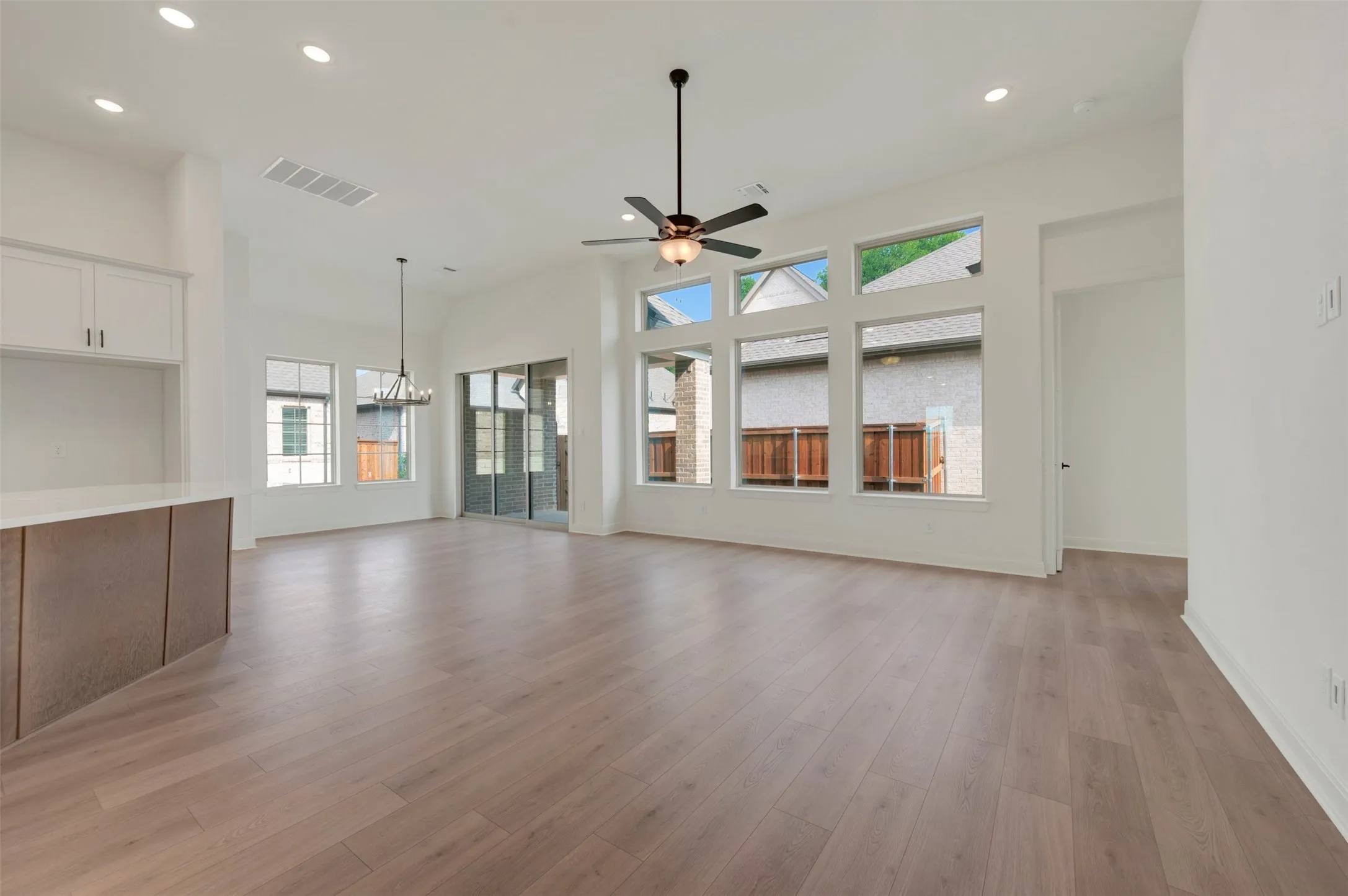 Spacious living area featuring wood-finish flooring, high ceilings, recessed lighting, and a contemporary ceiling fan