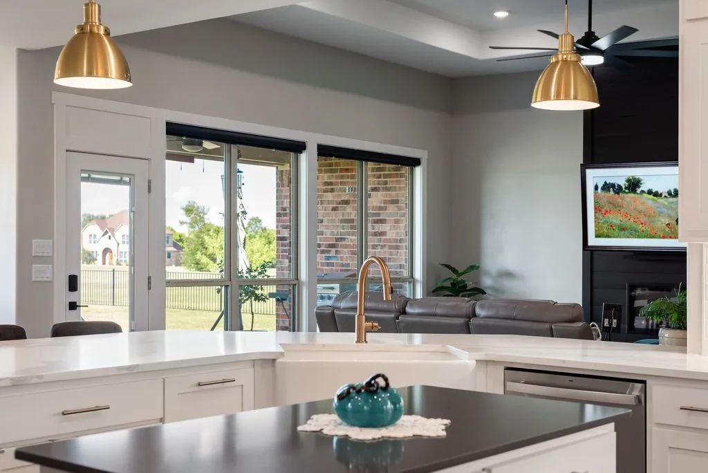 Kitchen with a large island featuring a white farmhouse sink and a bronze-finish faucet