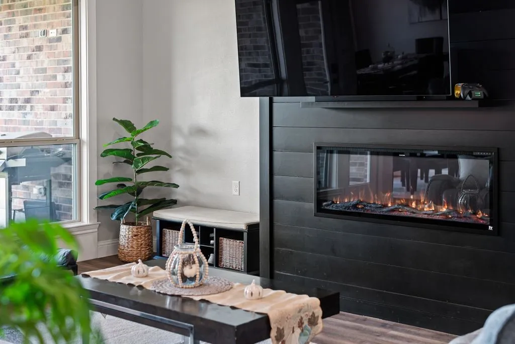 Built-in electric fireplace with a black shiplap surround, wood-finish flooring, and a large window with white trim