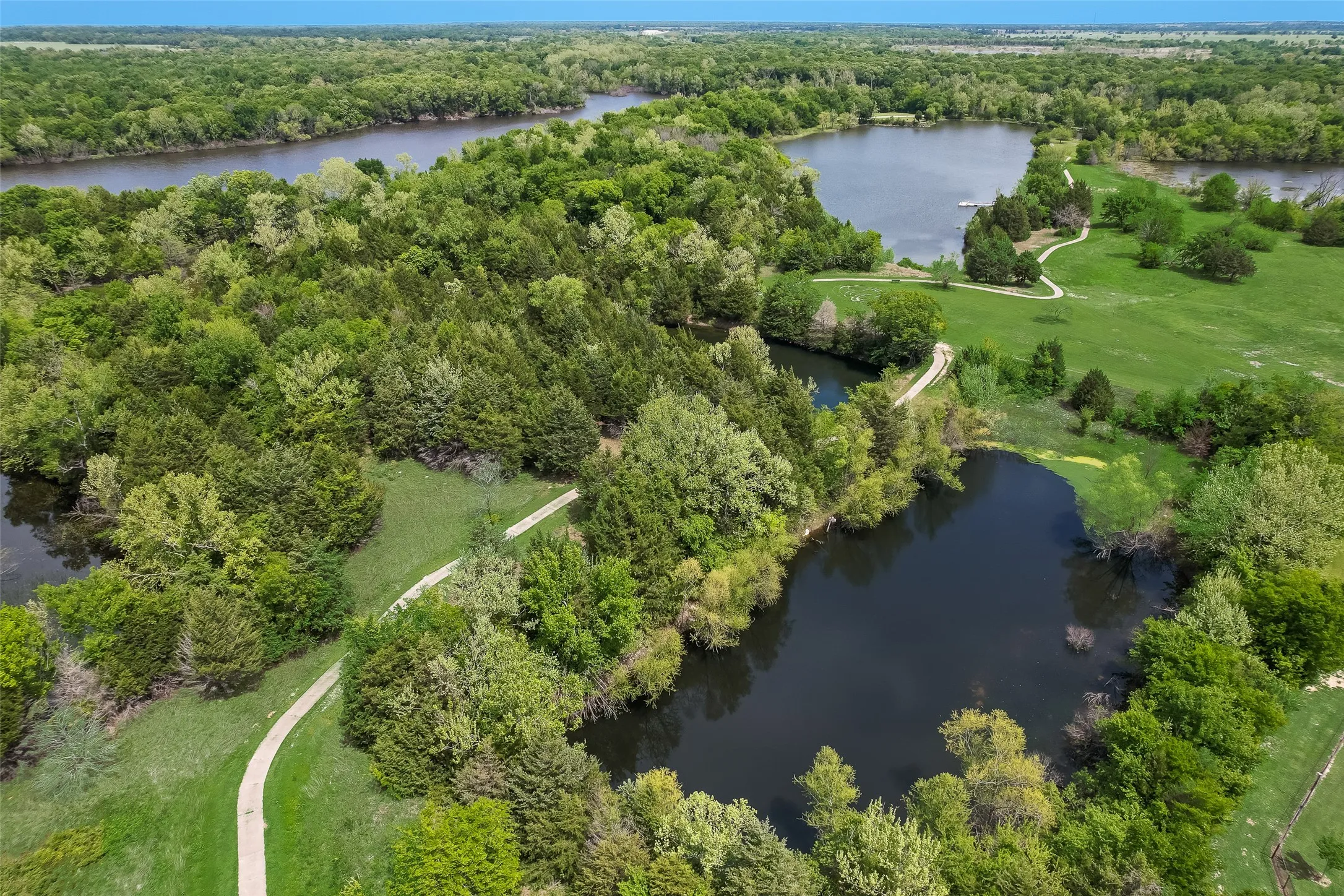 Expansive natural surroundings featuring multiple bodies of water, dense tree coverage, and meandering pathways