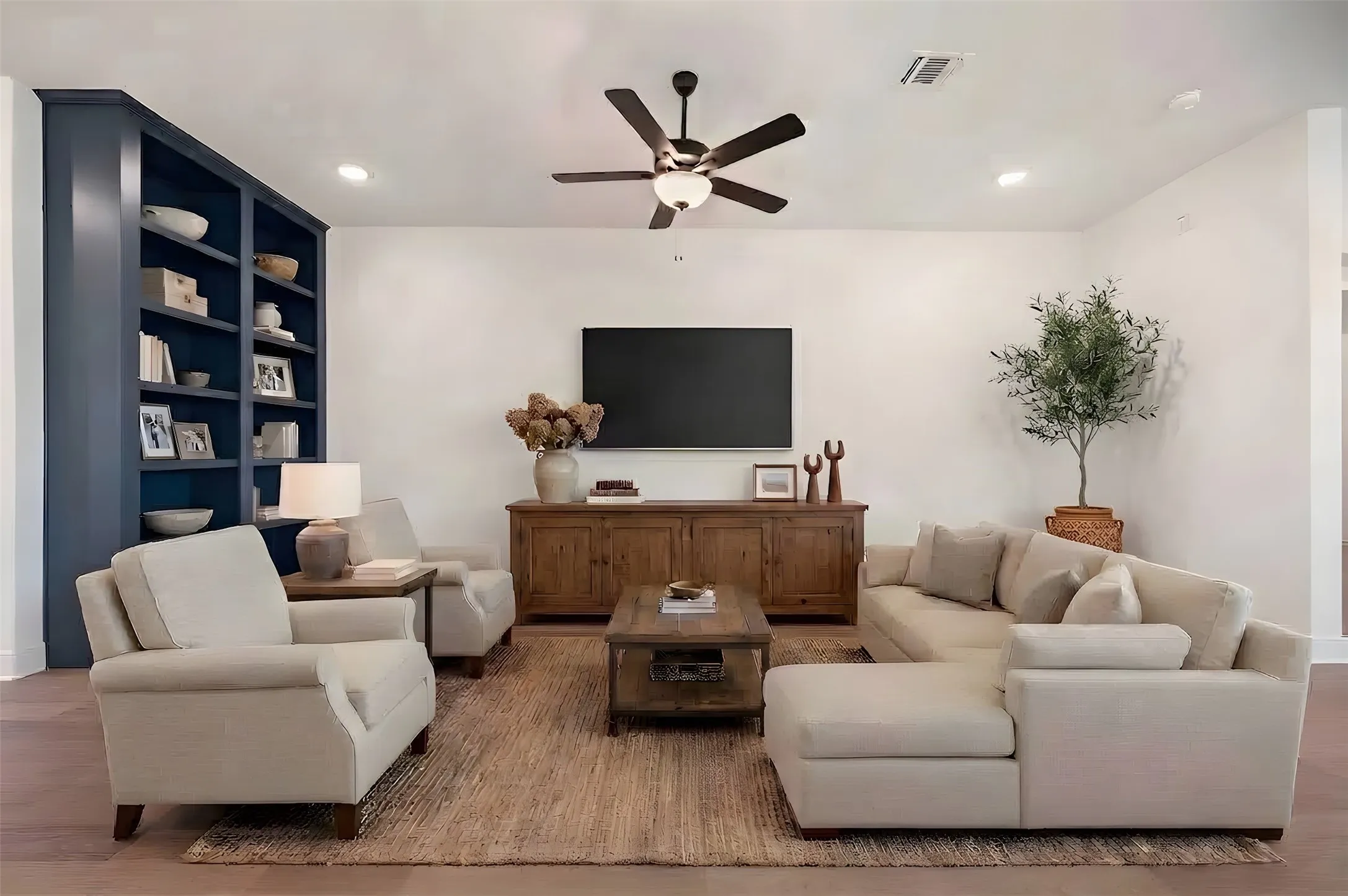 Wood-finish flooring, built-in shelving, ceiling fan with integrated lighting, recessed lighting, and white walls