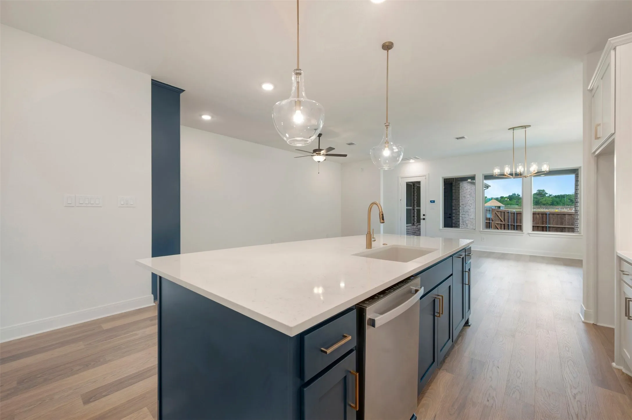The kitchen features a large island with a white countertop and dark cabinetry, equipped with a sink and a gold-toned faucet