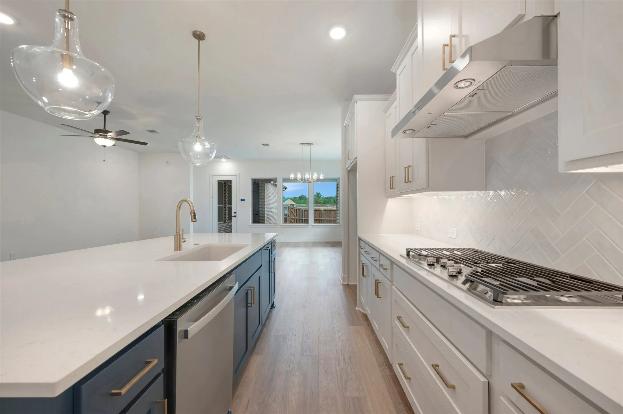 The kitchen features white shaker-style cabinets, a gas stovetop, and a herringbone-patterned tile backsplash