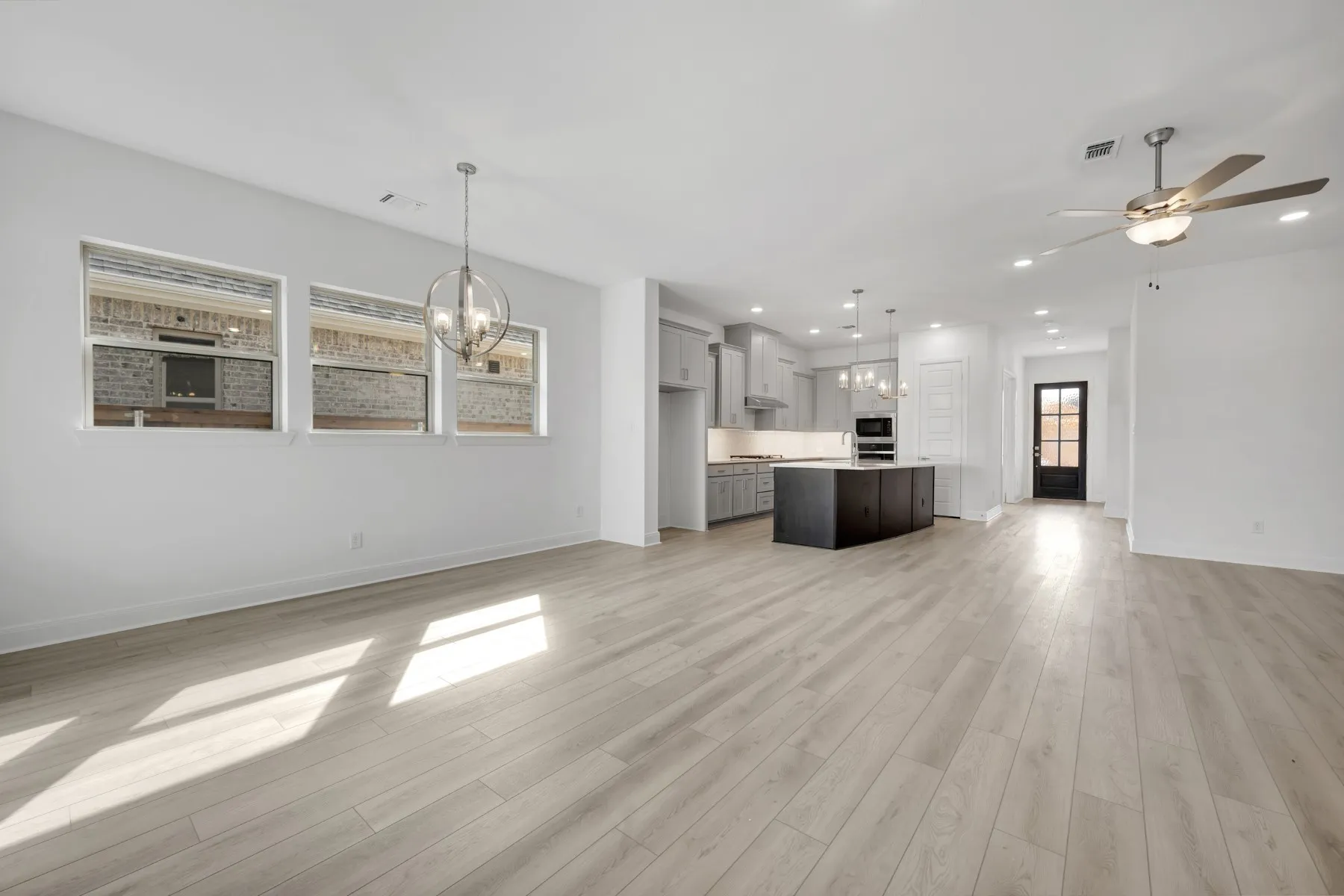 Unfurnished living room with a chandelier, a ceiling fan, and light wood finished floors