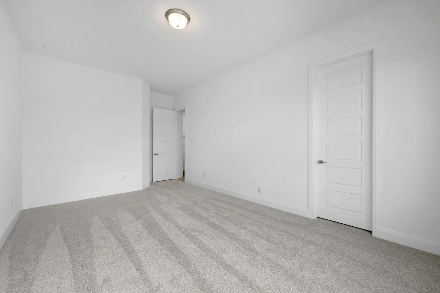 Spare room featuring light colored carpet and baseboards
