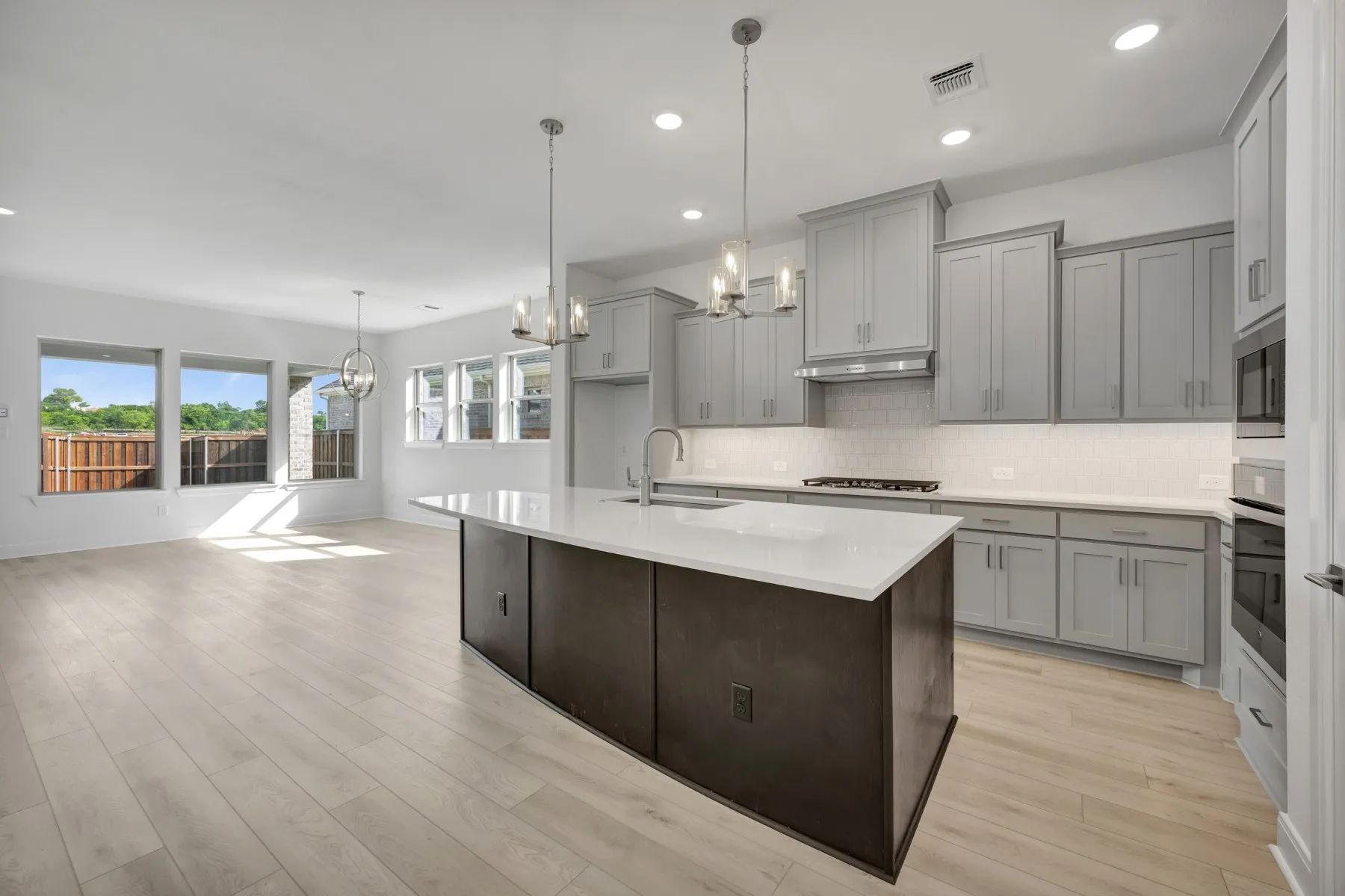Kitchen featuring a chandelier, gray cabinetry, a kitchen island with sink, stainless steel appliances, and light wood-style floors