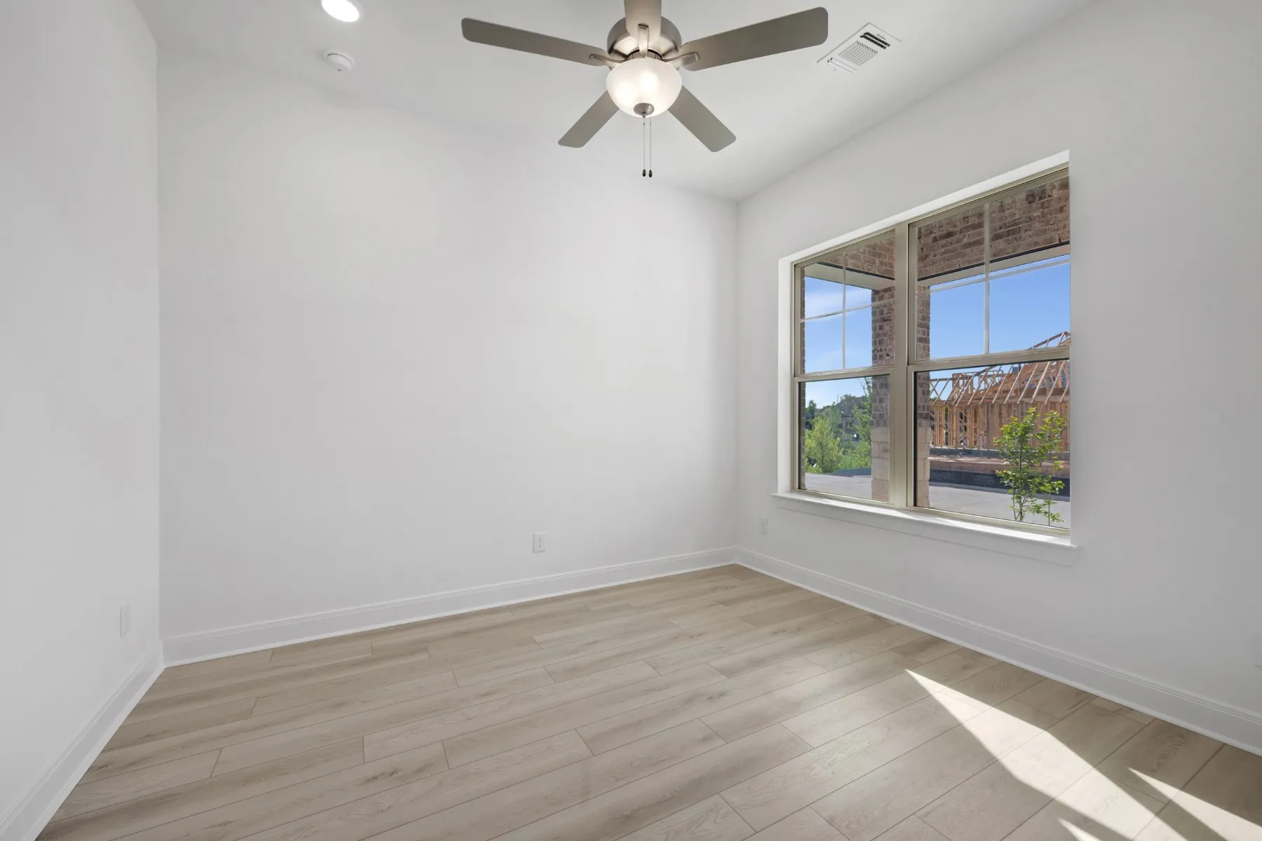 Empty room featuring light wood finished floors, ceiling fan, and recessed lighting